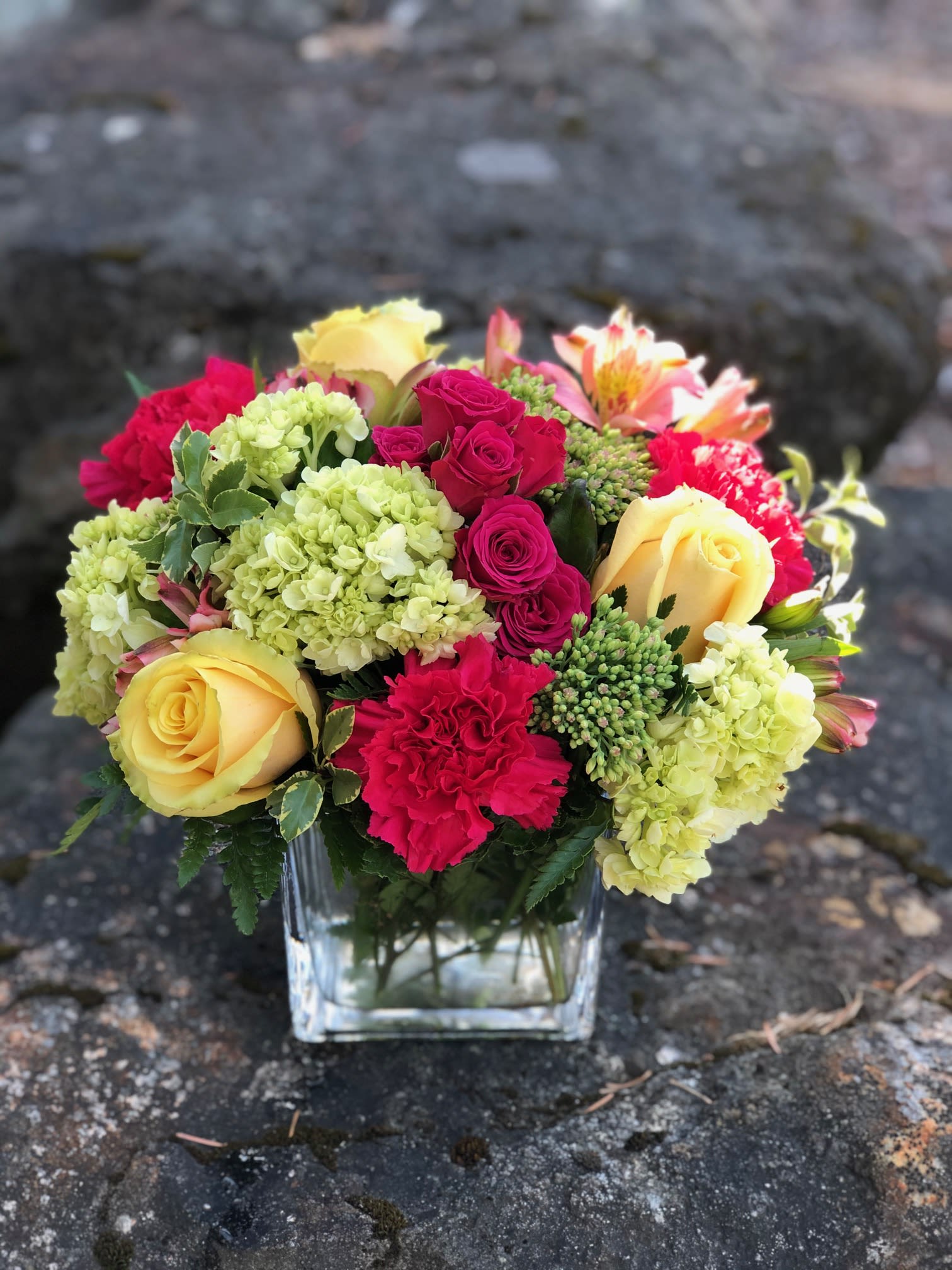 Mixed bouquet of yellow and pink flowers in a clear glass vase