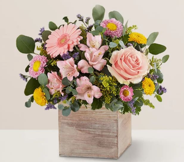 Mixed pink and yellow flowers in a wooden box