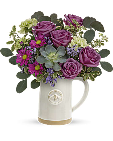 Purple roses and daisies arranged in a white ceramic mug