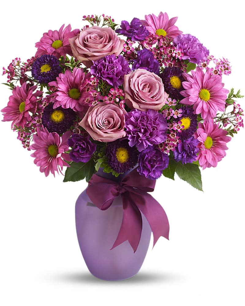 Purple and pink mixed flower arrangement in a lavender vase with a bow