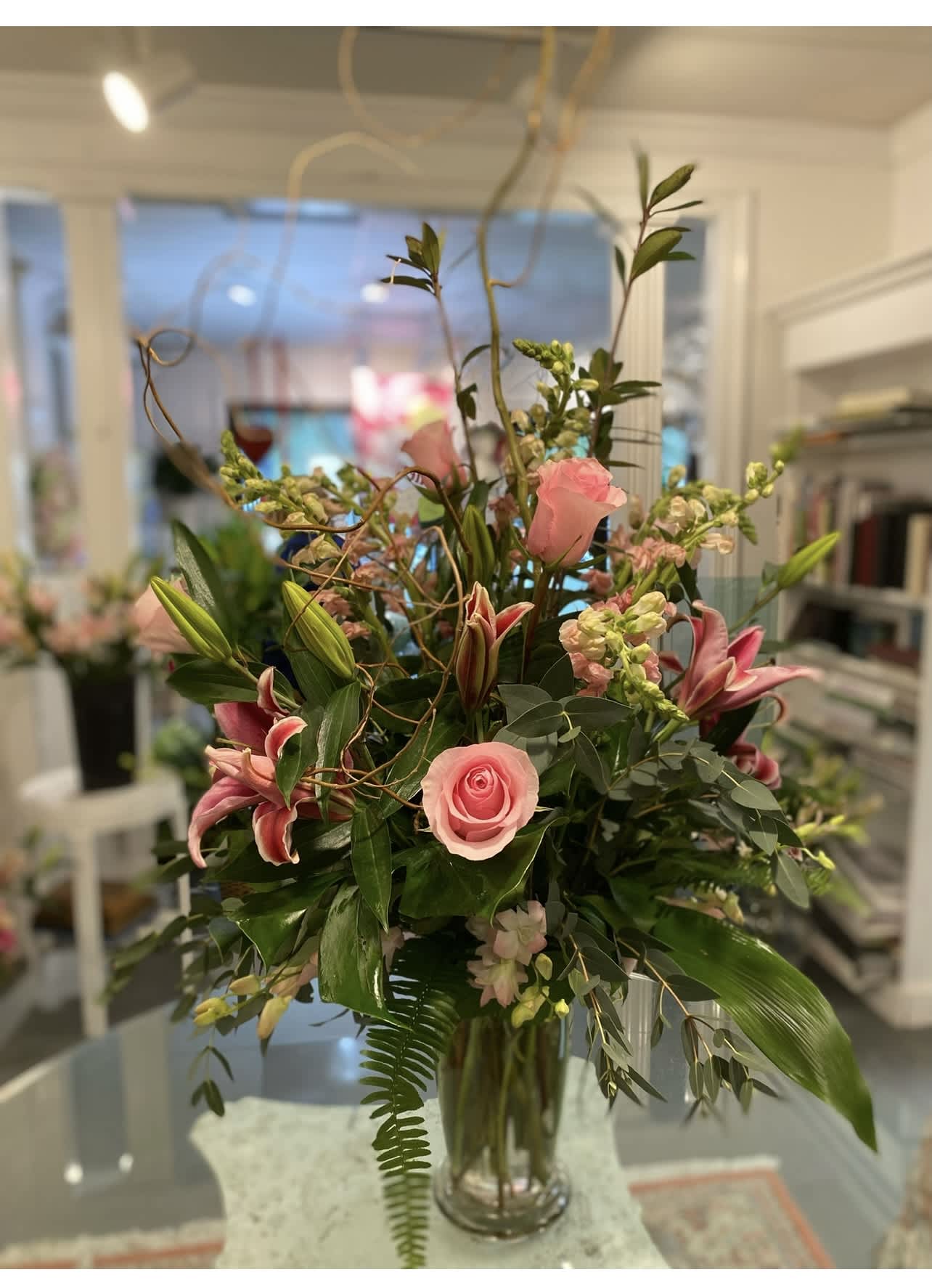 Tall bouquet of pink roses and lilies in a clear glass vase