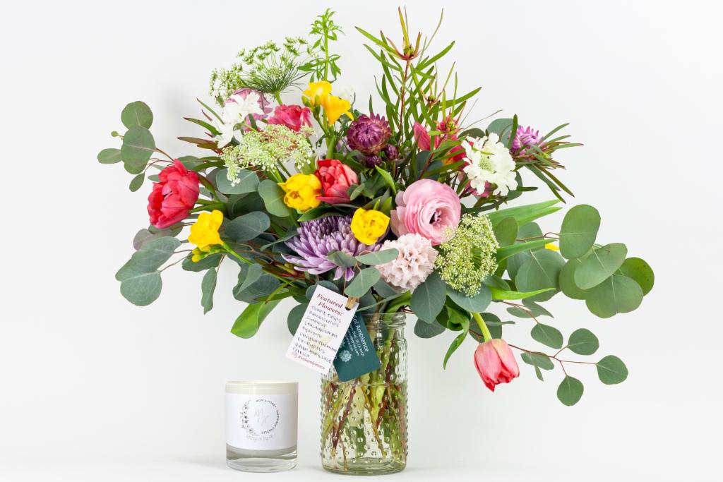 Mixed bouquet in a glass vase with a candle beside it