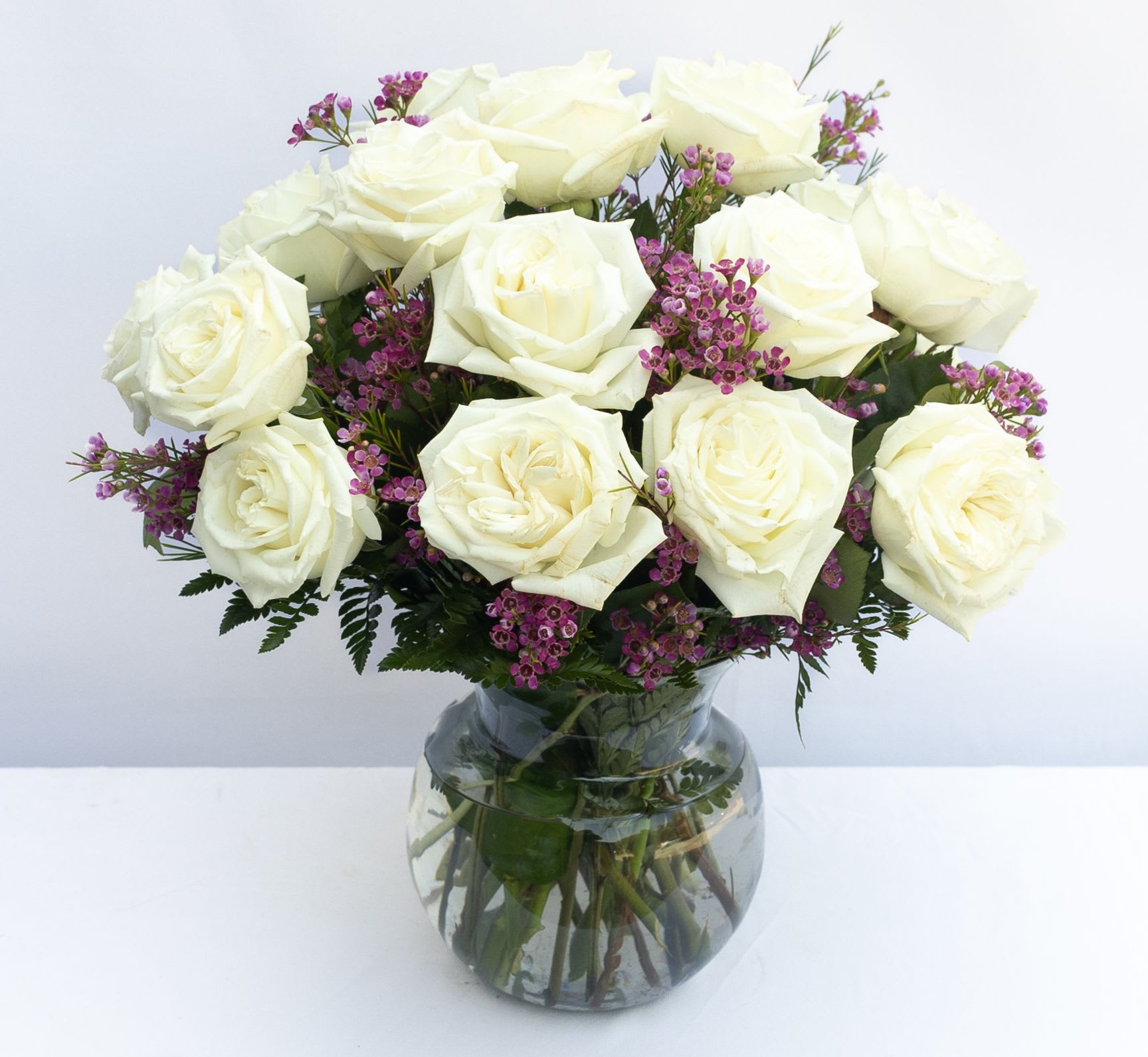 Monticello Rose Bouquet - The simple beauty of these white roses is accentuated by soft pink waxflower in a rounded bowl vase.  