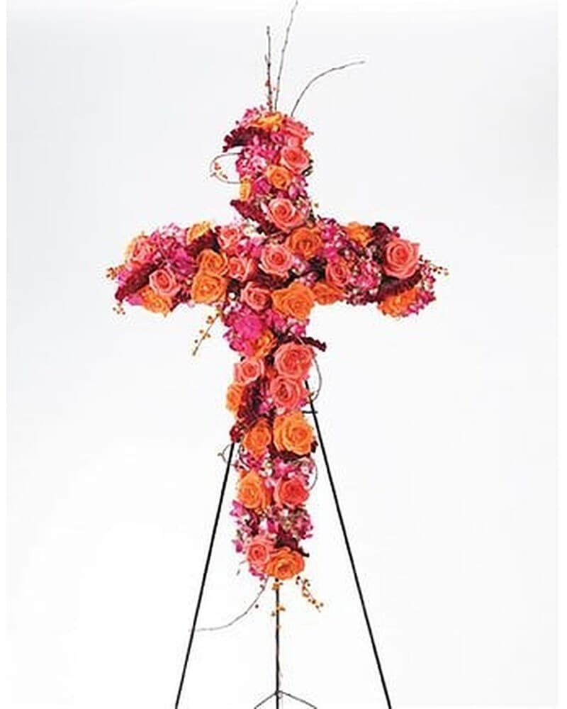Tall cross-shaped funeral spray of orange and pink roses on a metal easel stand