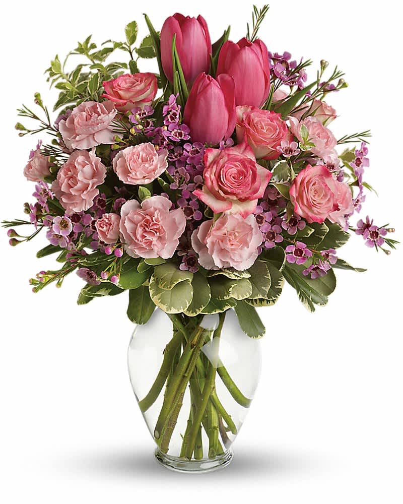 Pink tulips, roses, carnations, and small purple flowers arranged in a clear glass vase.