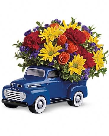 Blue toy truck filled with red, yellow, orange, and purple flowers