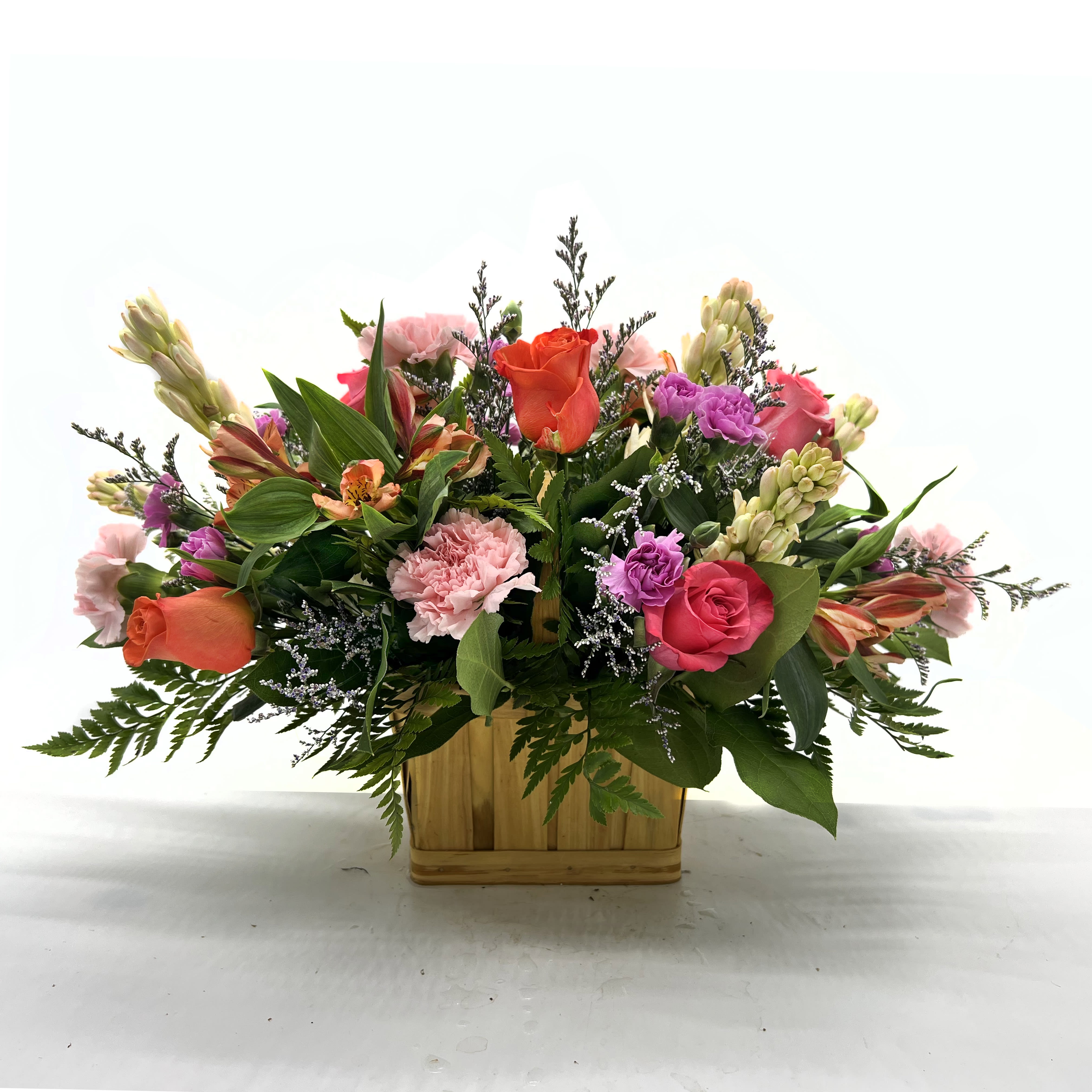 Mixed bouquet in a wooden basket with pink, orange, and purple flowers