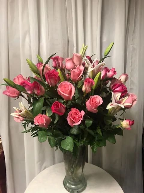Pink roses and lilies arranged in a clear glass vase
