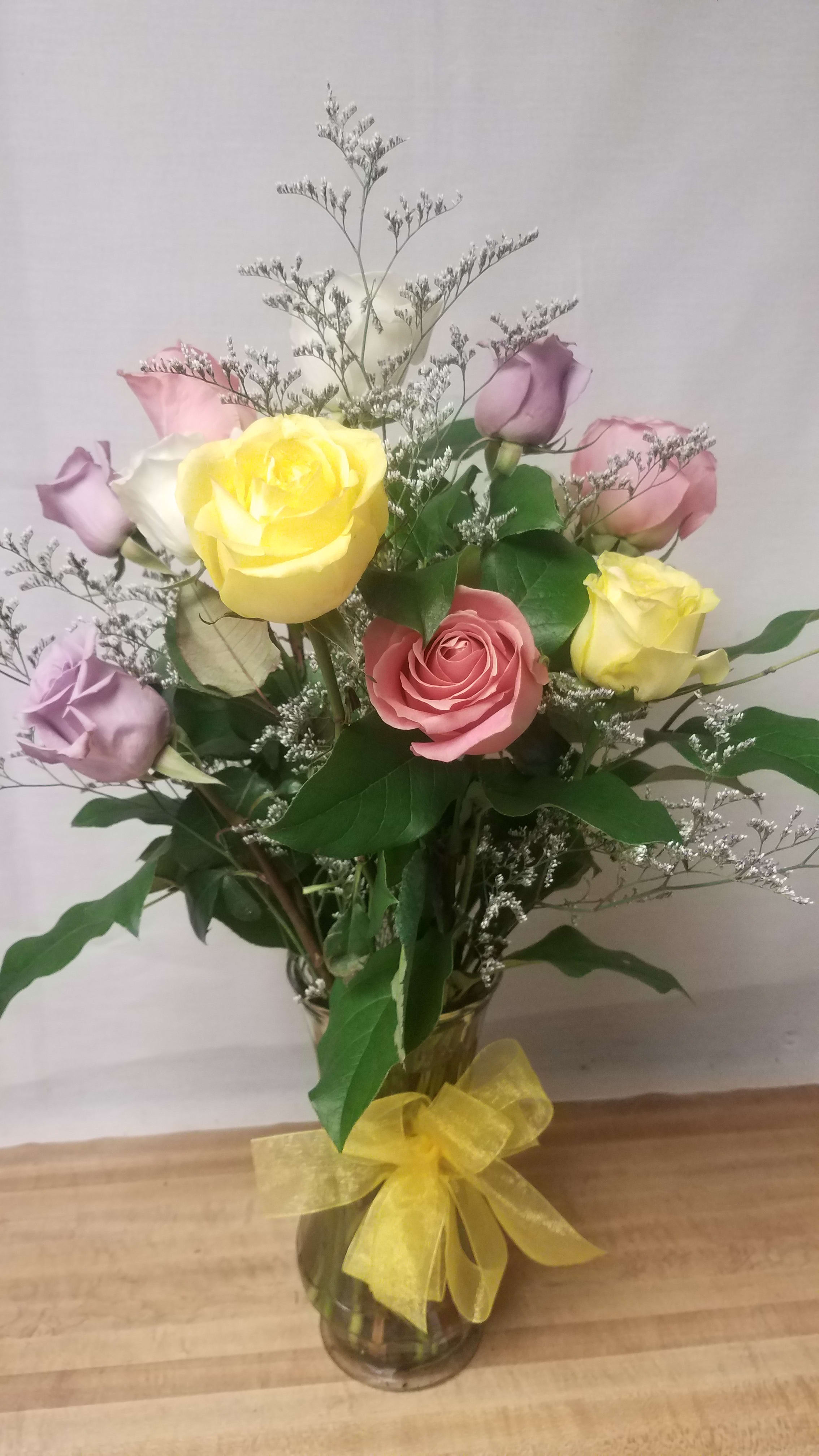 Bouquet of pastel roses in a glass vase with a yellow ribbon