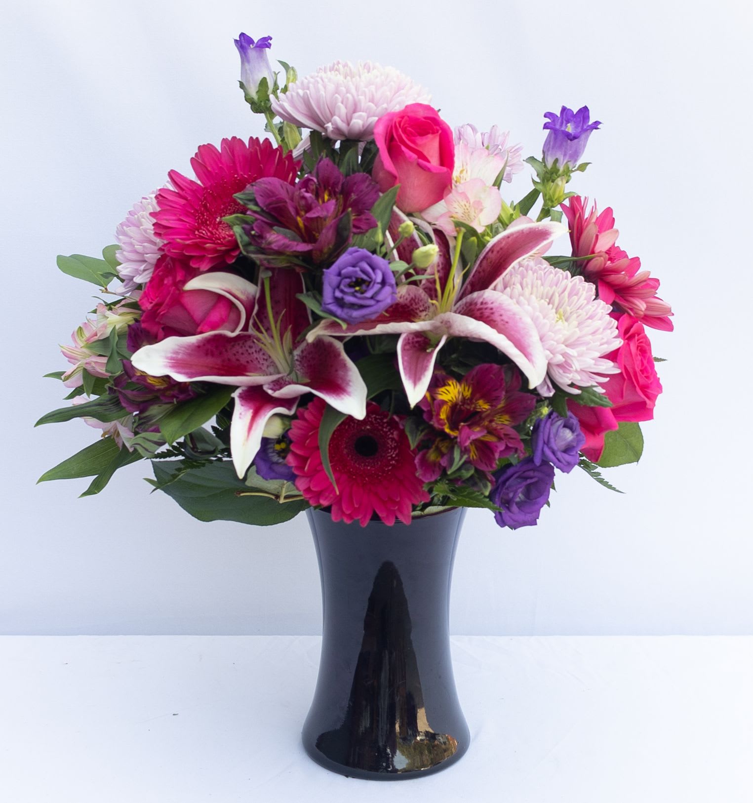 Mixed bouquet of pink, purple, and white flowers in a black vase