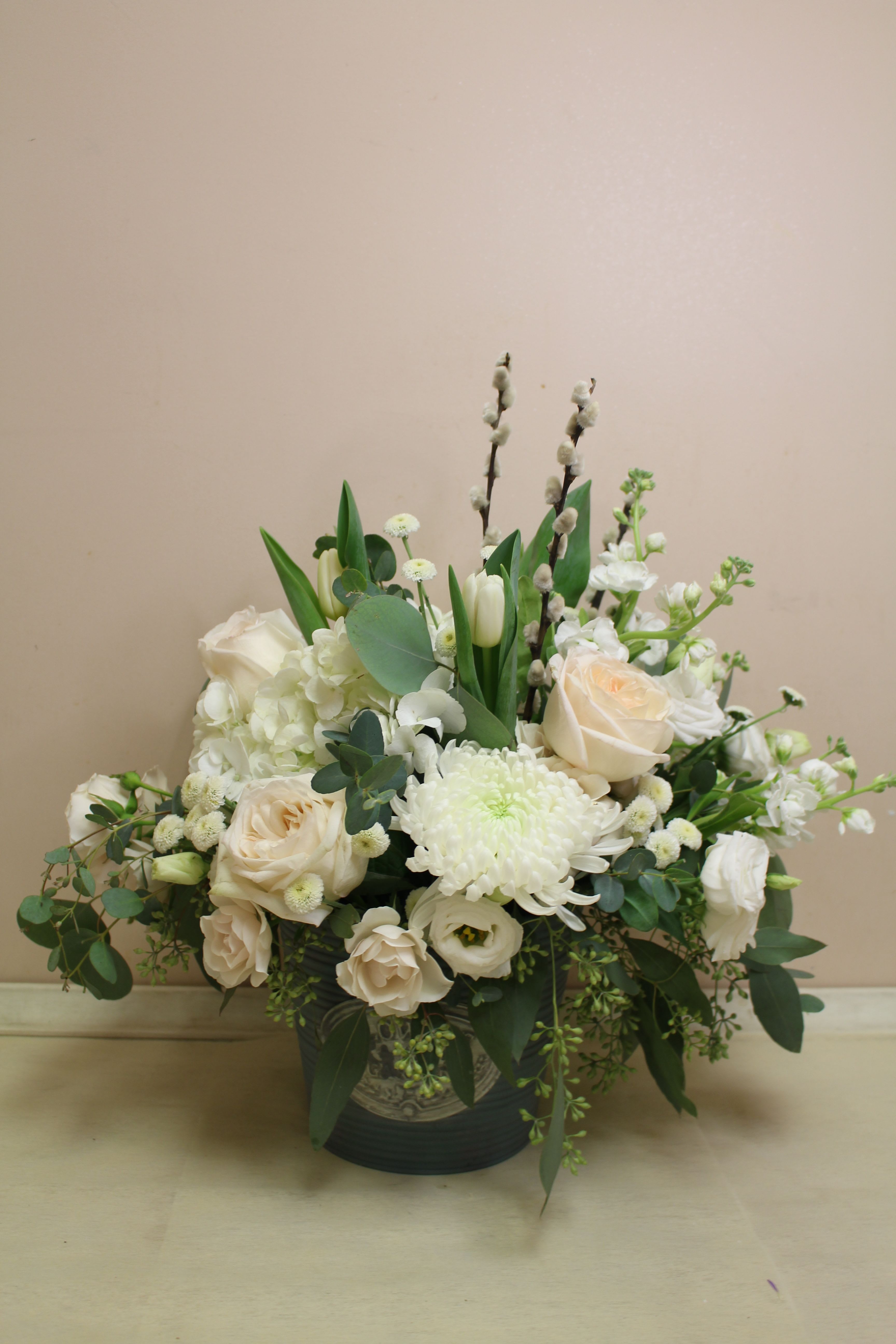 White floral arrangement in a dark vase with roses and chrysanthemums