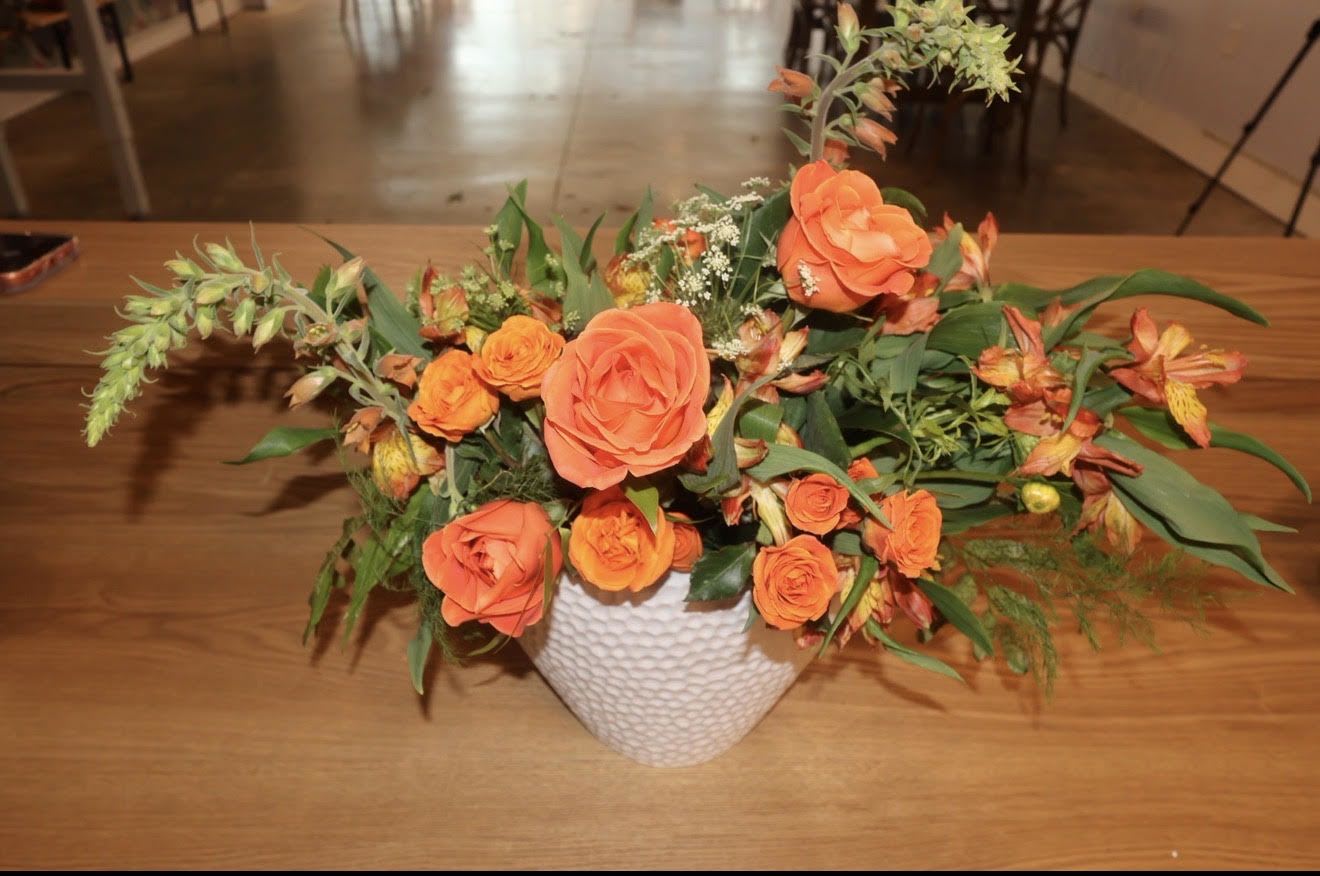 Orange rose arrangement in a white textured vase
