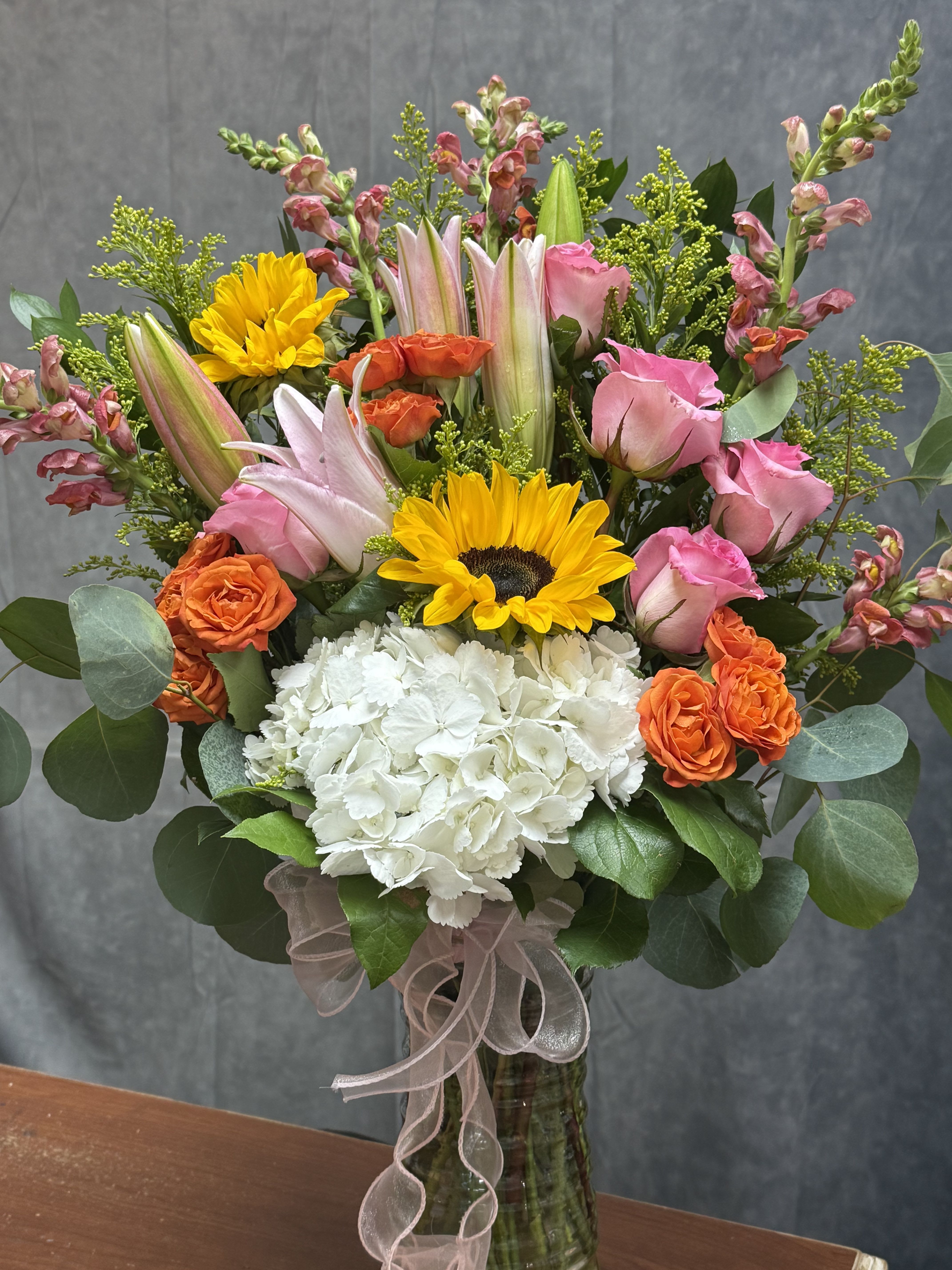 Happy Garden vase - The Happy Garden vase greets the recipient with a cheerful mix of warm and soft pastels-the bold yellow of sunflowers balanced by delicate pinks and a crisp white center-so the person you're thinking of feels instantly celebrated. This is the kind of bouquet that makes someone feel genuinely celebrated-ideal for moms, friends, coworkers, or hosts. Perfect for all occasions 