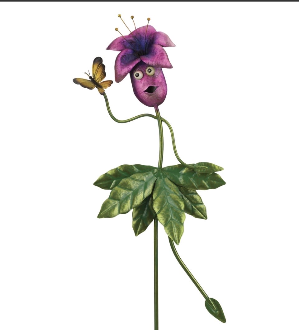 Be Jolly Garden Stake  - A playful purple metal bloom with a cheeky, face-like center and a tiny butterfly perched on an outstretched arm-this garden stake is a whimsical way to say "thinking of you" or bring summer cheer to Mother's Day and Father's Day celebrations. As a decorative flower sculpture for birthdays, Memorial Day displays, or a thoughtful thank-you gift, it reads as lighthearted home and garden décor that will make the person you're gifting it to smile every time they pass by.  Hand-painted metal petals in saturated purple combine with glossy black accents, layered green leaves at the base, and a slender stem that adds height and presence to beds, planters, or indoor pots. The piece includes a butterfly ornament and an iridescent sheen that catches the light, giving it three-dimensional personality without any watering or care. Durable and weather-resistant, it's also suitable for Fourth of July garden vignettes, Earth Day plantings, or as a get-well brightener for someone recovering at home-no maintenance required, just place it where it will be seen and enjoyed.