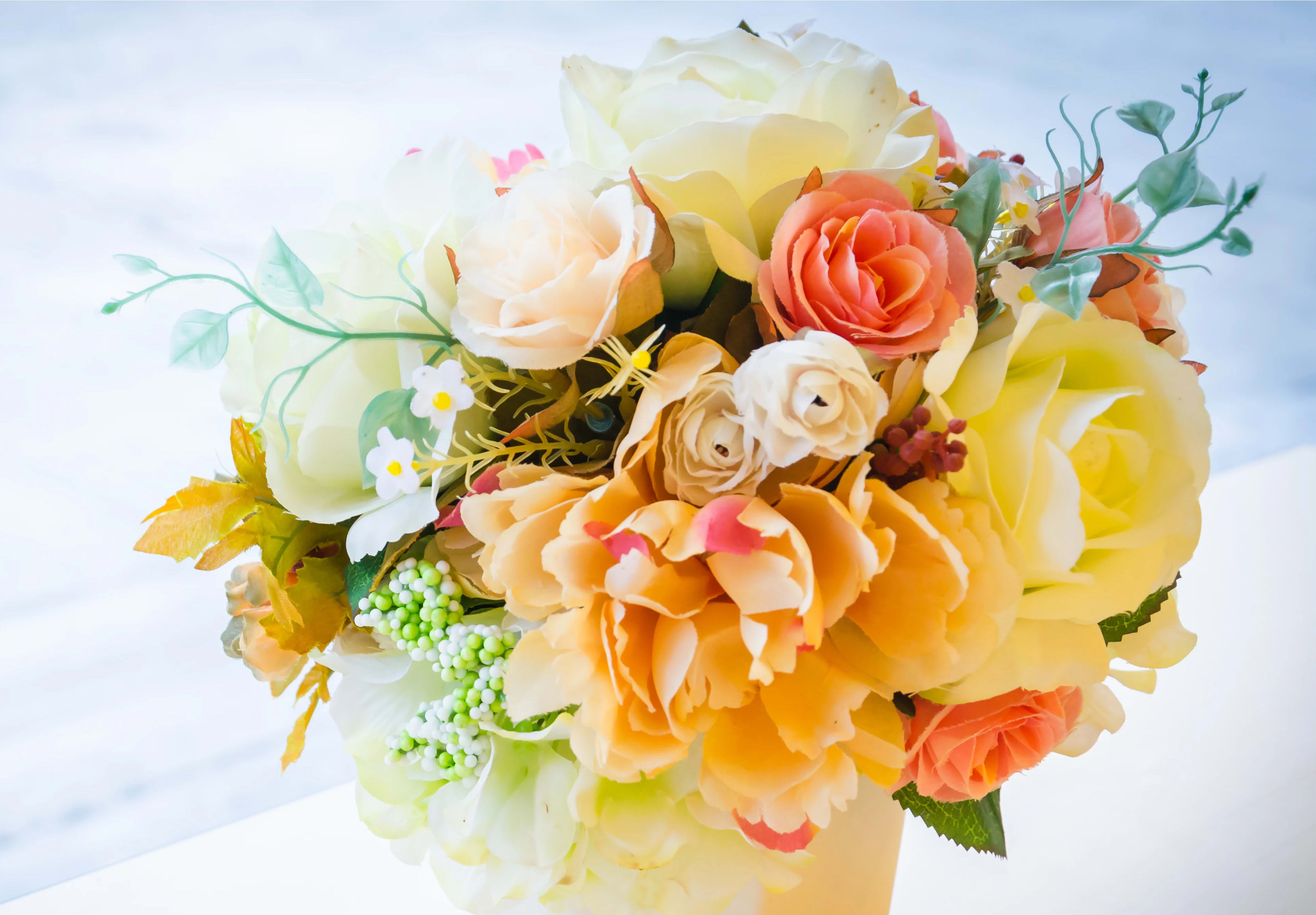 Bouquet of cream, peach, and yellow roses with small white accents