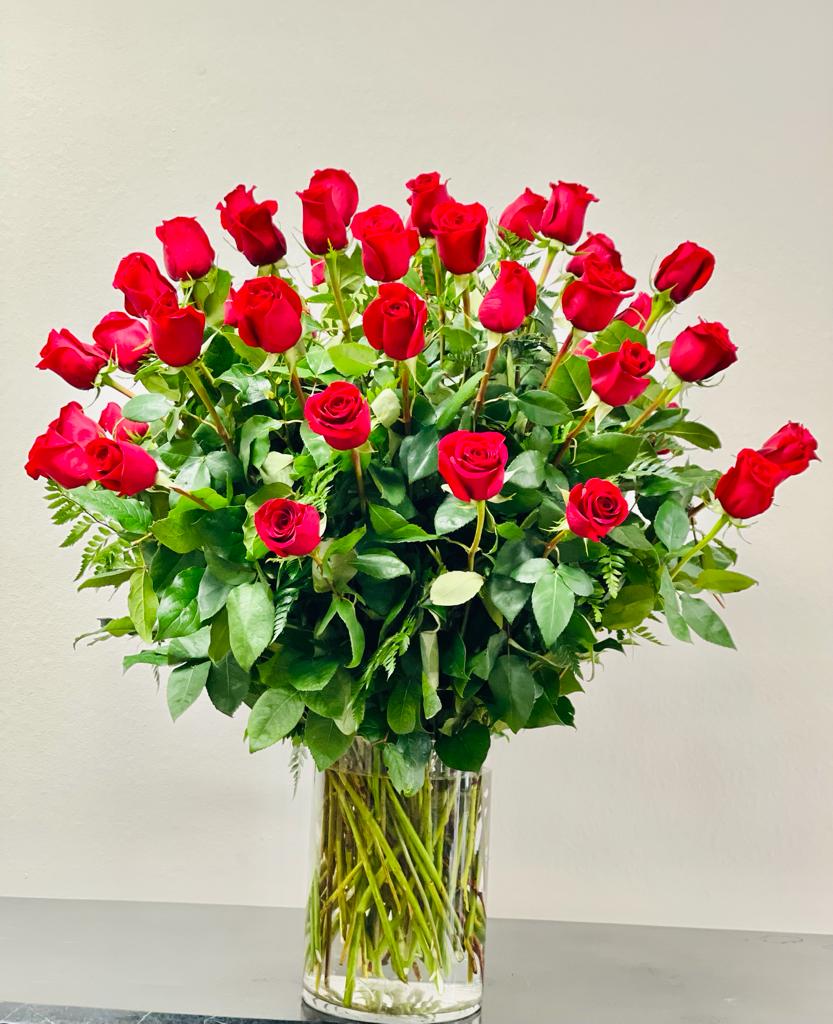 Tall bouquet of red roses in a clear glass vase