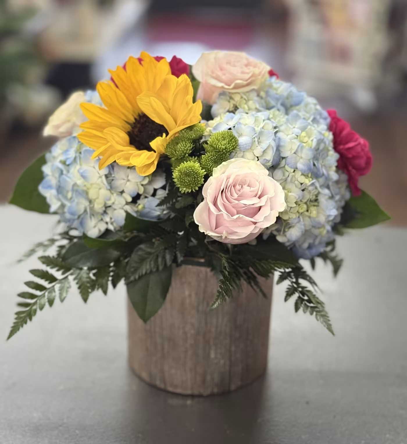 Loving Legacy - Mixed pastels with hydrangeas, roses, sunflower and buttons arranged in a rose gold ceramic container.  