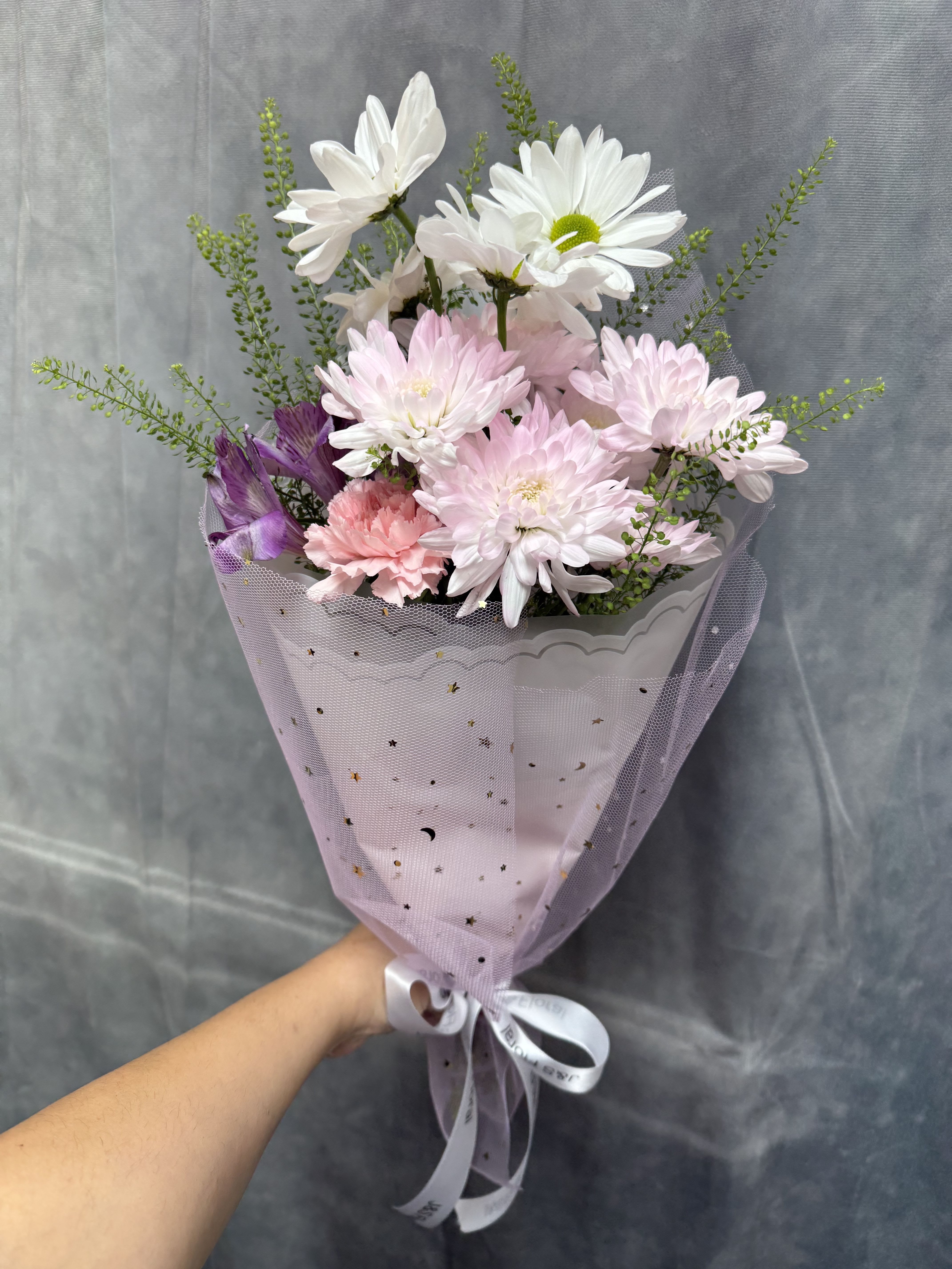 Blush daydream bouquet  - Pink and white daisies with a pink carnation and purple accents, wrapped in lavender mesh with white ribbon-fresh, cheerful bouquet perfect for birthdays, thank-yous, or Mother's Day.