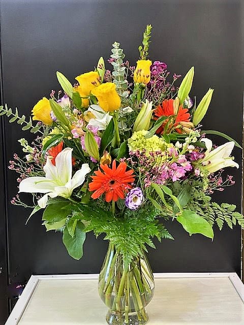 Mixed bouquet of lilies, gerbera daisies, and roses in a glass vase