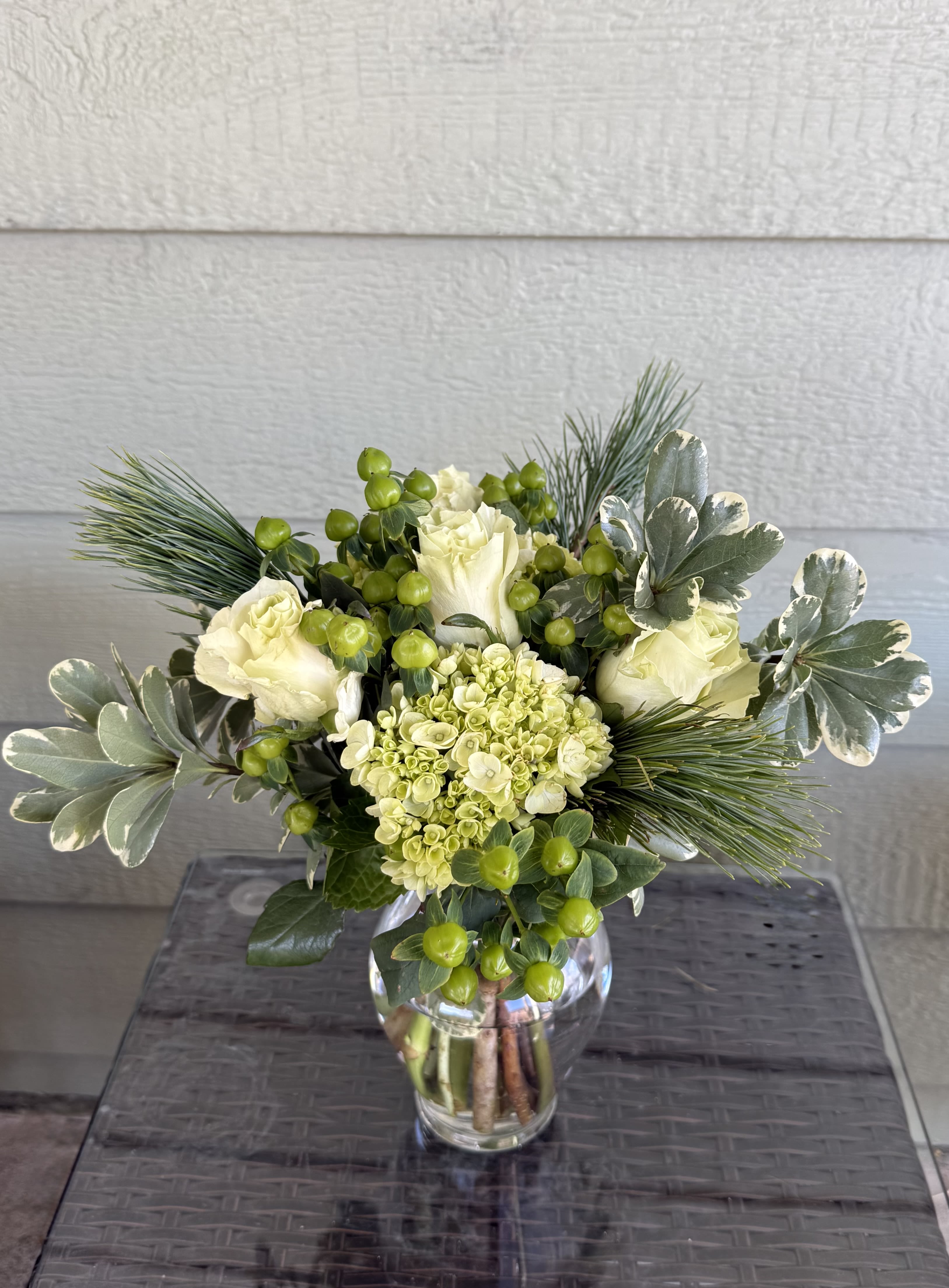 Merry Grinchmas - Steal the show (not Christmas) with our Merry Grinchmas arrangement! Bursting with fresh winter greens, creamy roses, cheerful green hydrangea, and whimsical berry accents, this design is full of festive mischief and holiday charm.  Perfect for the Grinch at heart. This joyful green-and-cream arrangement brings a fresh twist to holiday florals—fun, festive, and guaranteed to make spirits grow three sizes. 