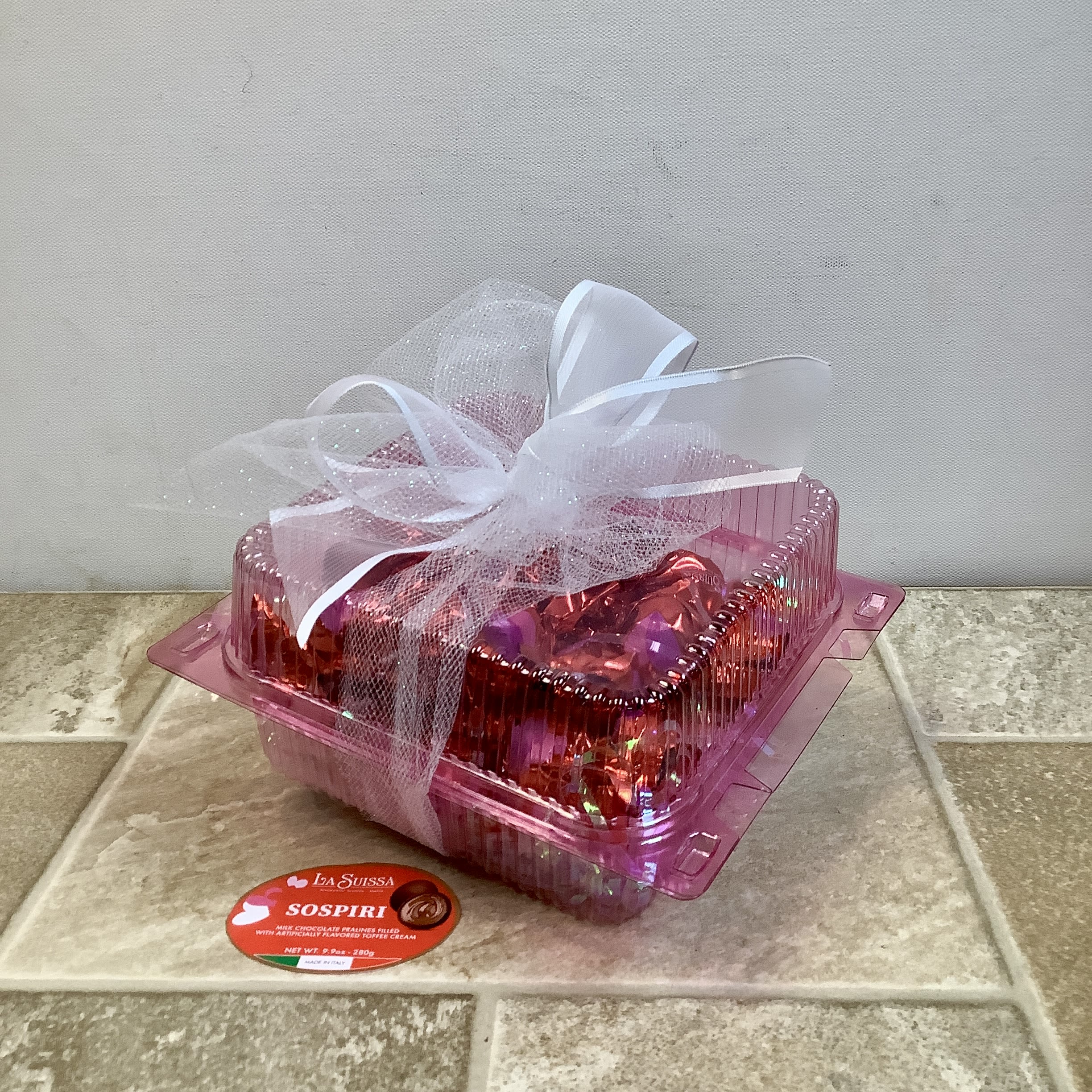 Pink gift box tied with white ribbon and tulle, with a candy label in front