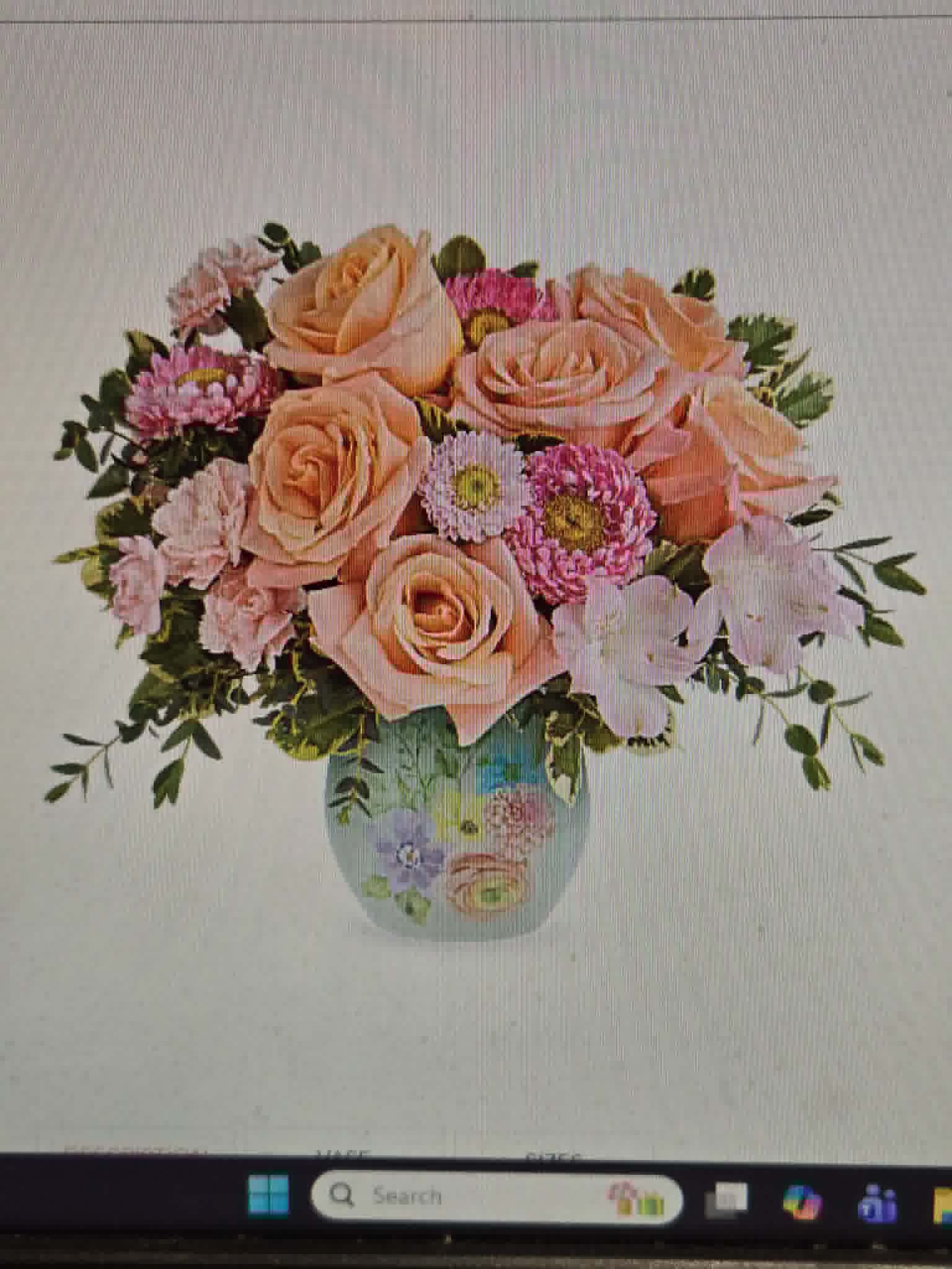 Sky and Petal - Soft peach roses and pale pink carnations mingle with cheerful pink daisy-like blooms in a rounded garden-style arrangement-an ideal birthday bouquet, anniversary surprise, or "thinking of you" gift that feels gentle and romantic. The soft pink, peach, white, and green palette creates a warm, uplifting impression that will make the person you're thinking of feel truly seen and cherished.  Gathered to spill outward from a hand-painted metal vase, the full, rounded design highlights the roses as focal blooms while the daisies and carnations add delicate texture and softness. The compact yet generous composition works well as a centerpiece on a kitchen table or as a bright bedside surprise; vase is included and the arrangement arrives ready to display.