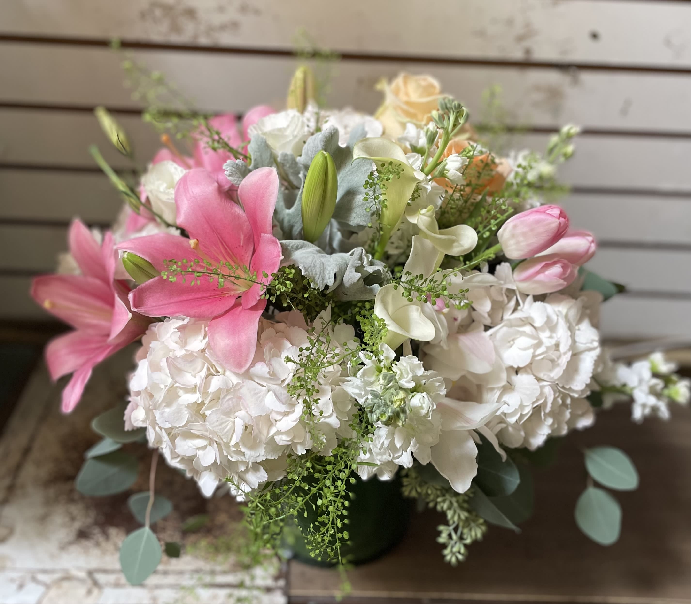 Pink lilies and white hydrangeas in a dark vase