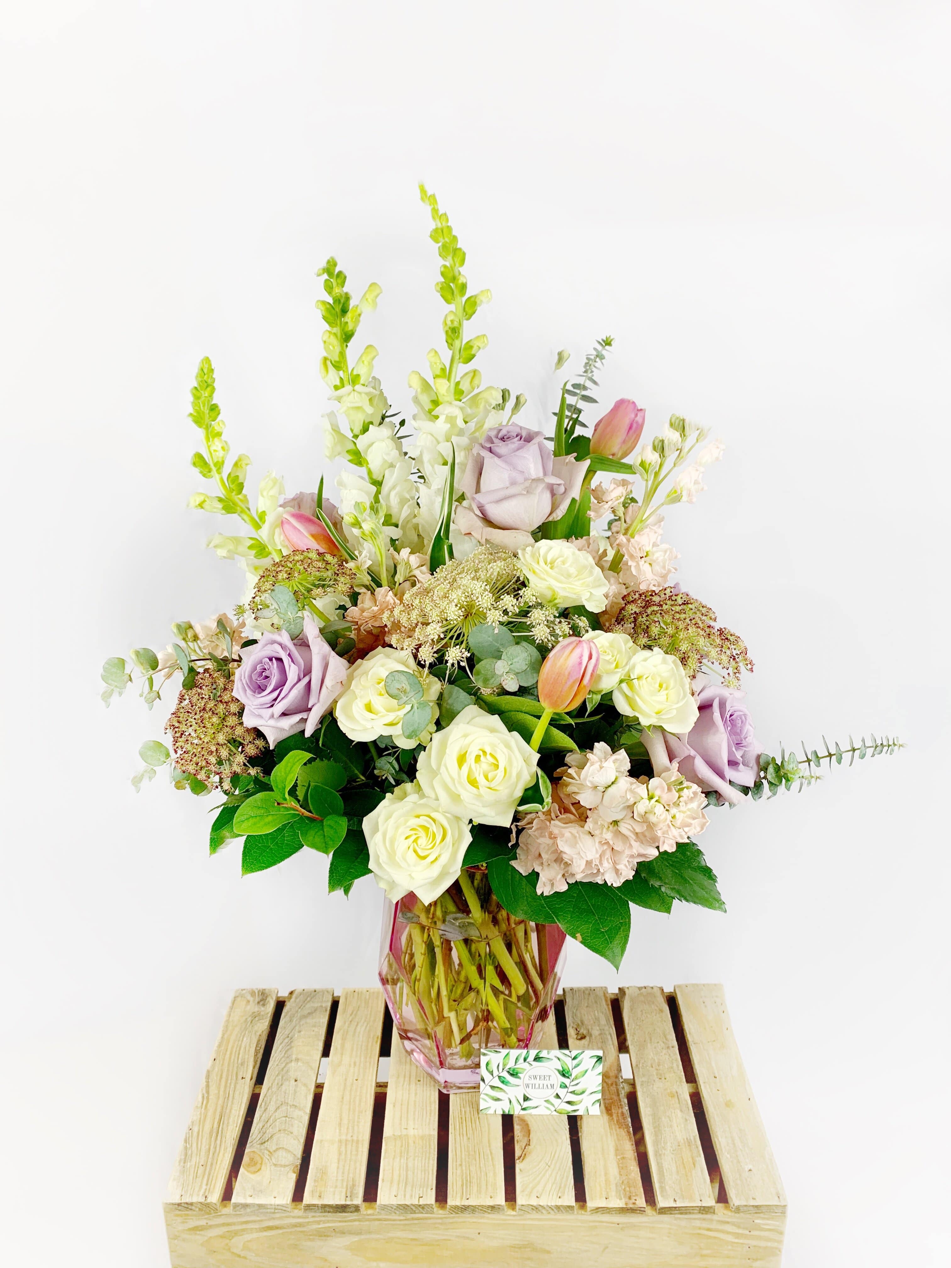 Lavender and white flower arrangement in a pink glass vase
