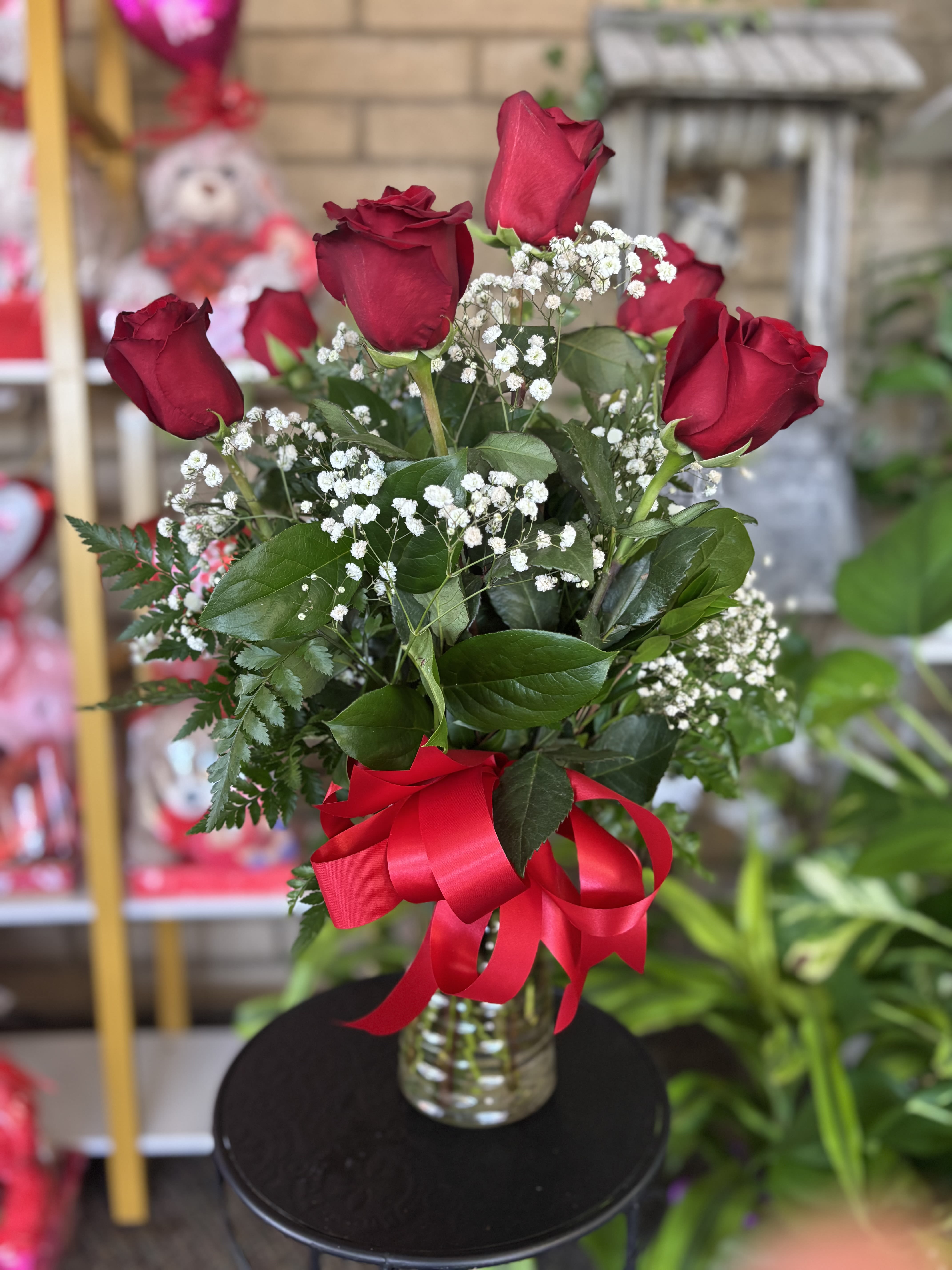 Red roses in a glass vase with baby's breath and a red ribbon
