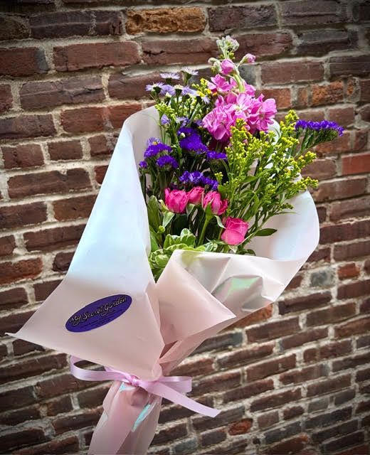 Mother's Hug- Wrapped Bouquet - The "Mother's Hug" is a bright and colorful bouquet of loose flowers wrapped in beautiful paper- this gift is perfect for the creative mom. Including Spray Rose, Aster, Stock and an assortment of unique filler flowers that are sure to show your love and brighten your mothers day. 