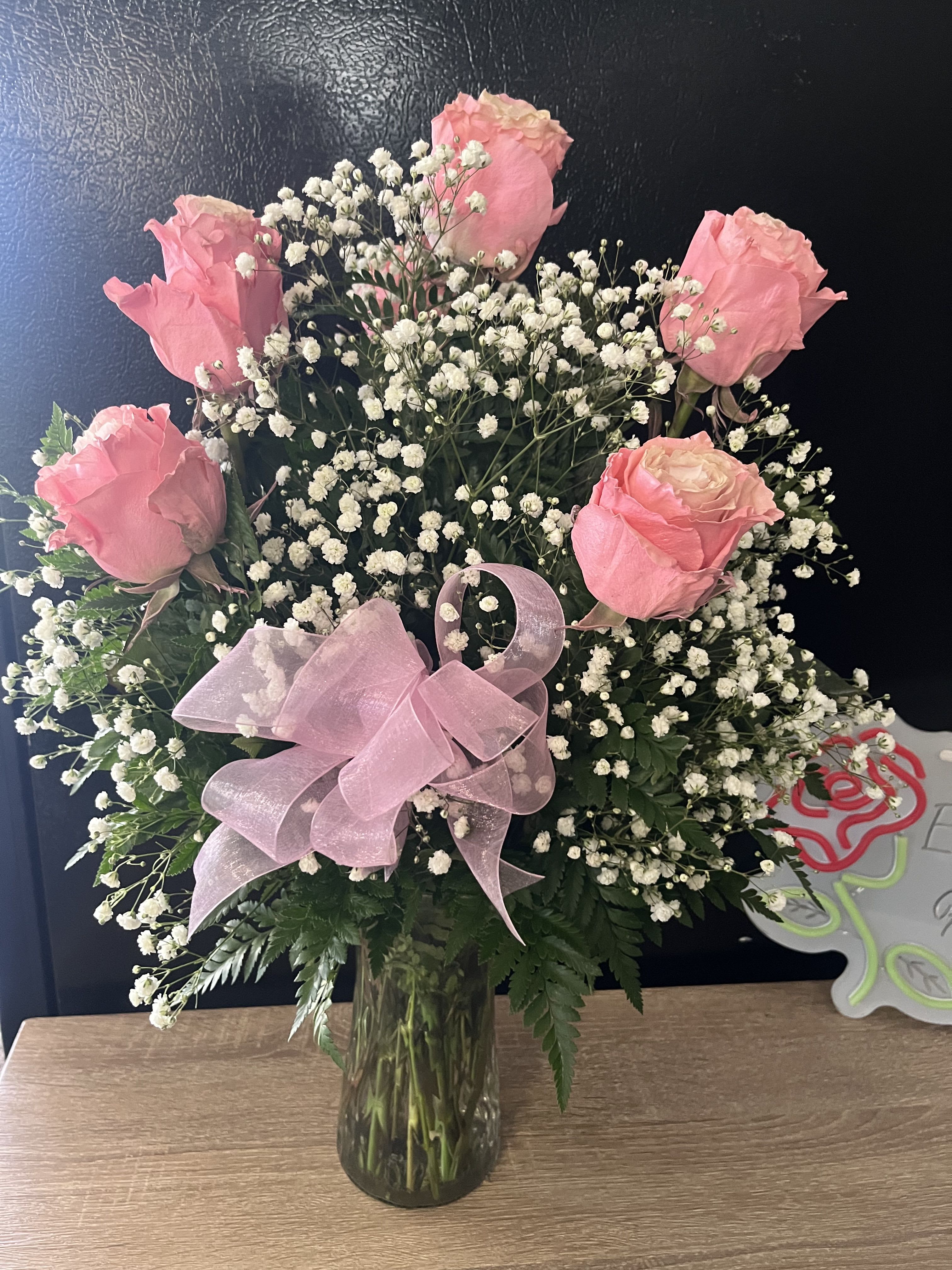Pink roses with baby's breath in a glass vase and pink ribbon