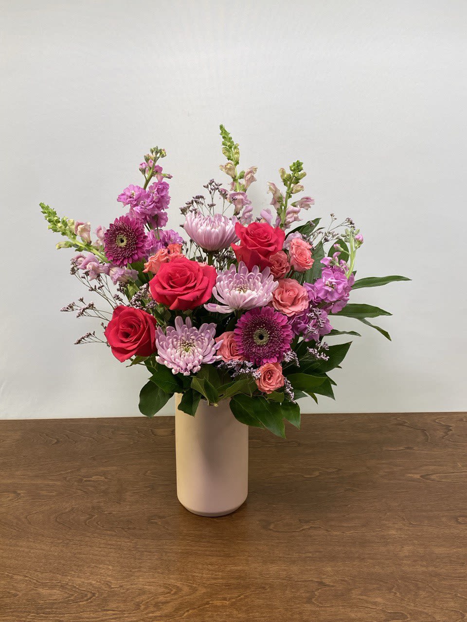 Mixed pink and purple flowers arranged in a white vase