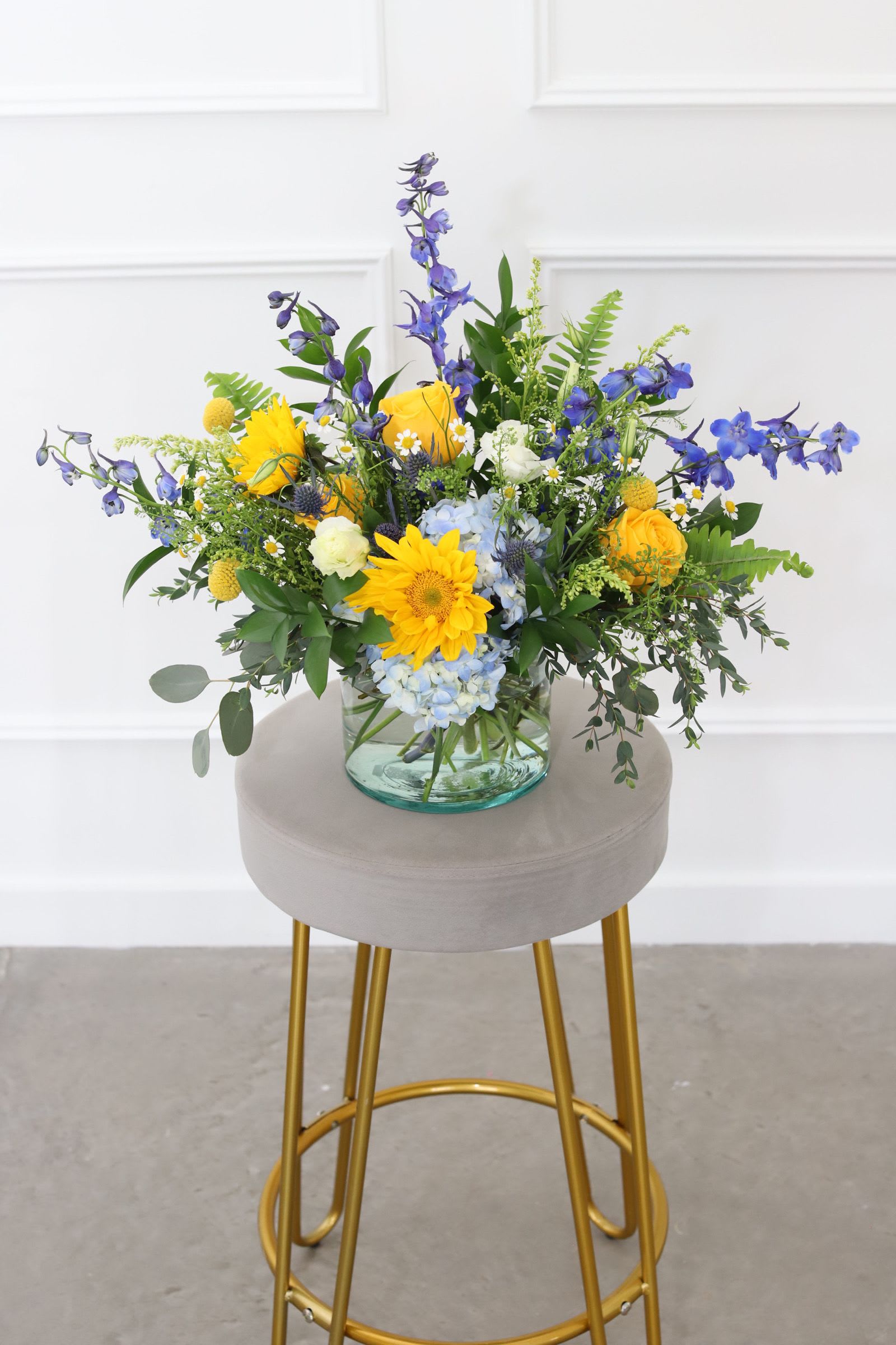 Mixed bouquet in a clear glass vase with yellow, blue, and white flowers