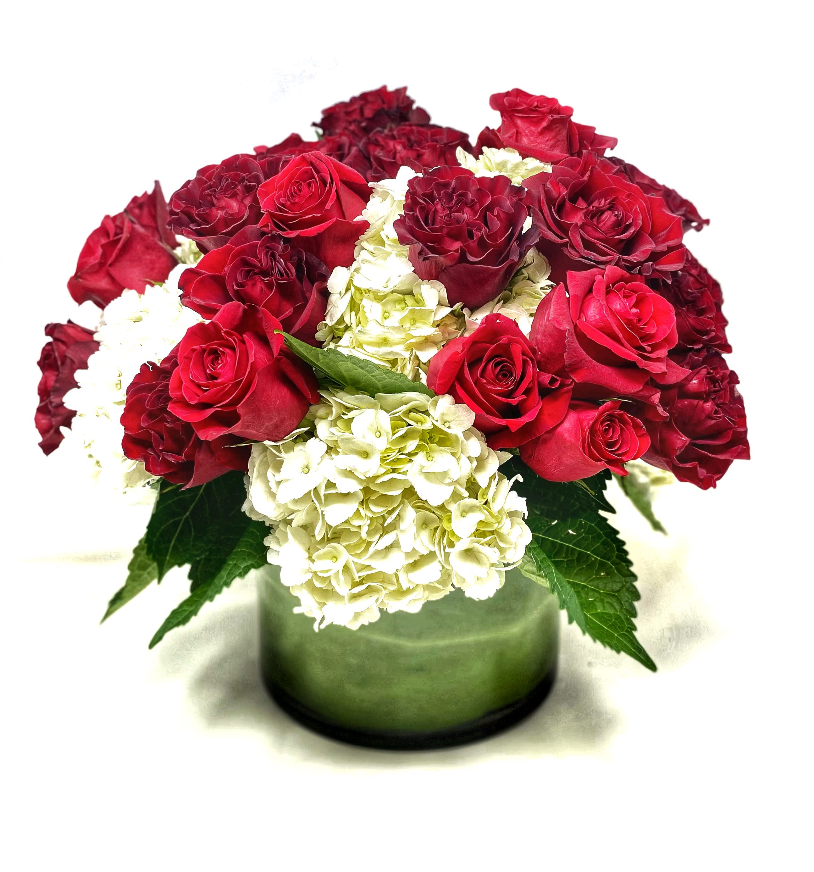 Red roses and white hydrangeas in a green glass vase