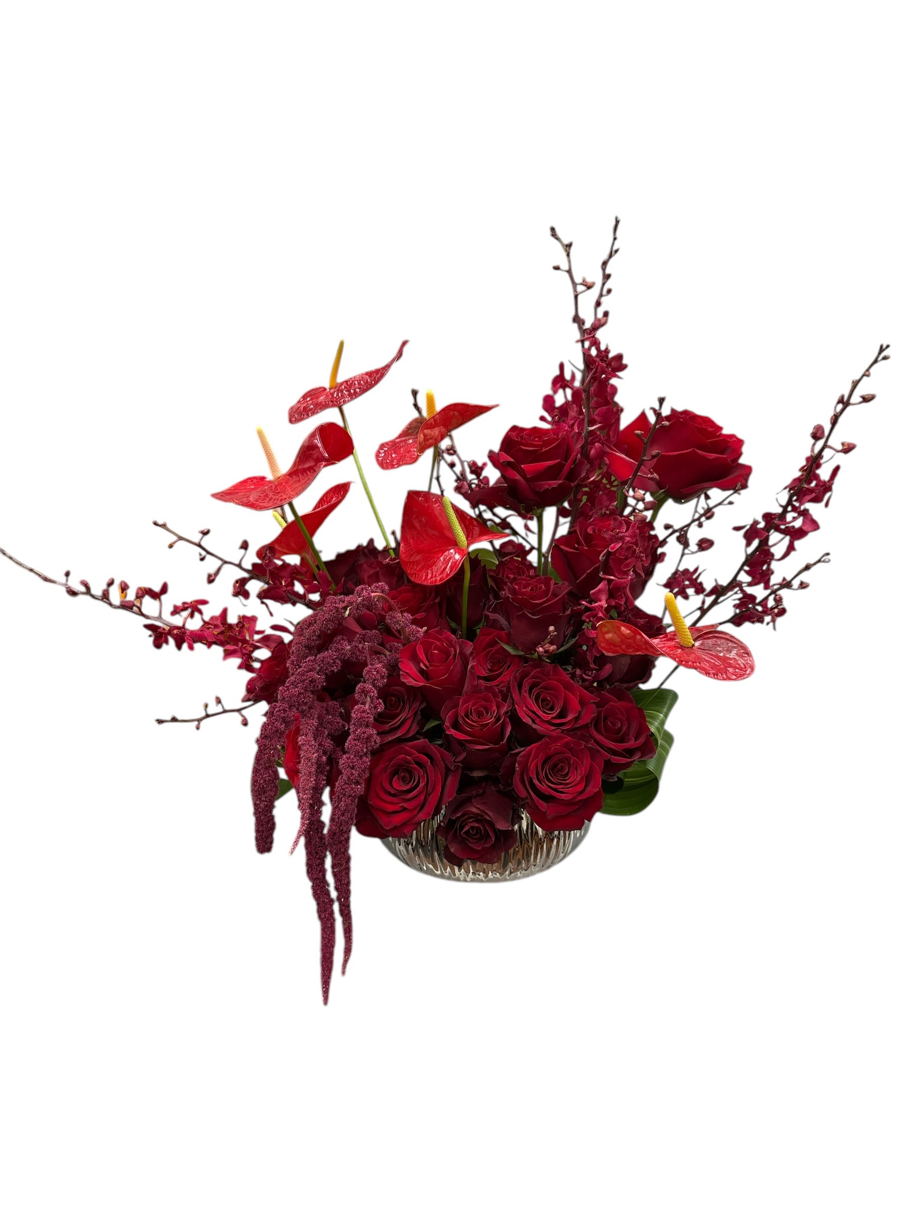 Red rose arrangement in a clear glass bowl with red anthuriums