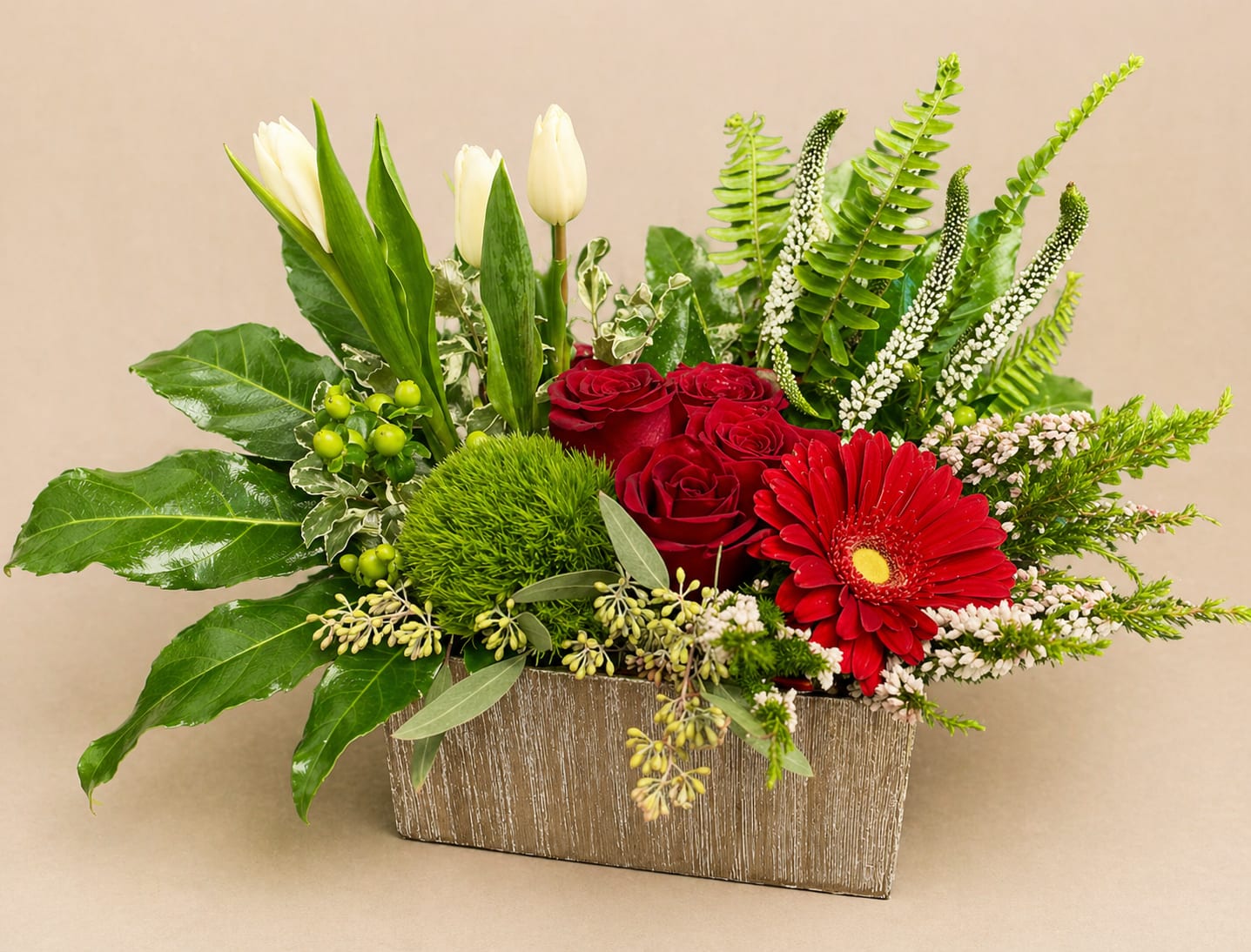 Red roses and a red gerbera daisy in a rectangular vase with white tulips
