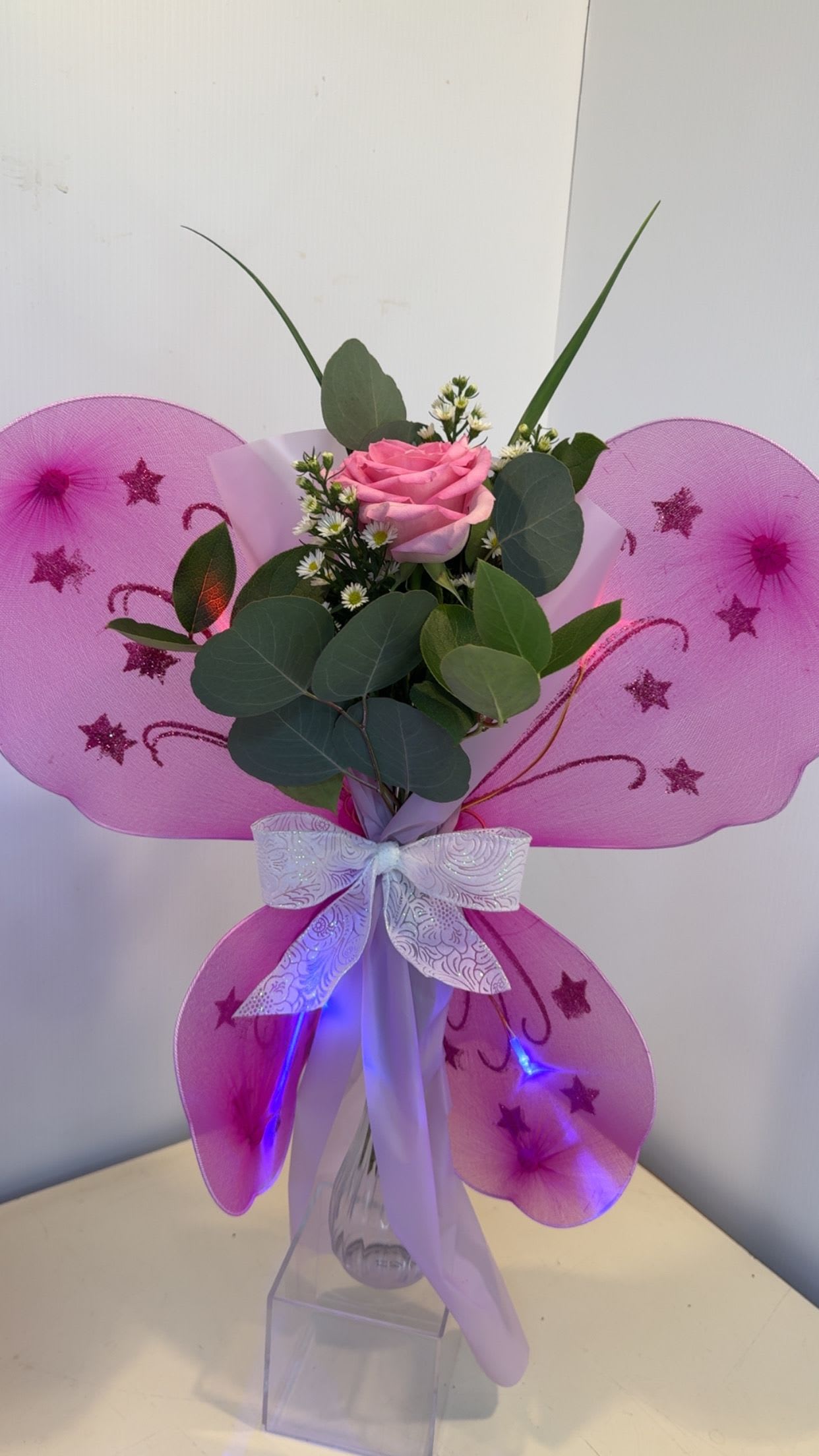 Dance LED Light Up Butterfly Wrap - A rose or Gerber accented with fresh greenery, filler, and sparkling butterfly wings that light up. Perfect for dance recitals!