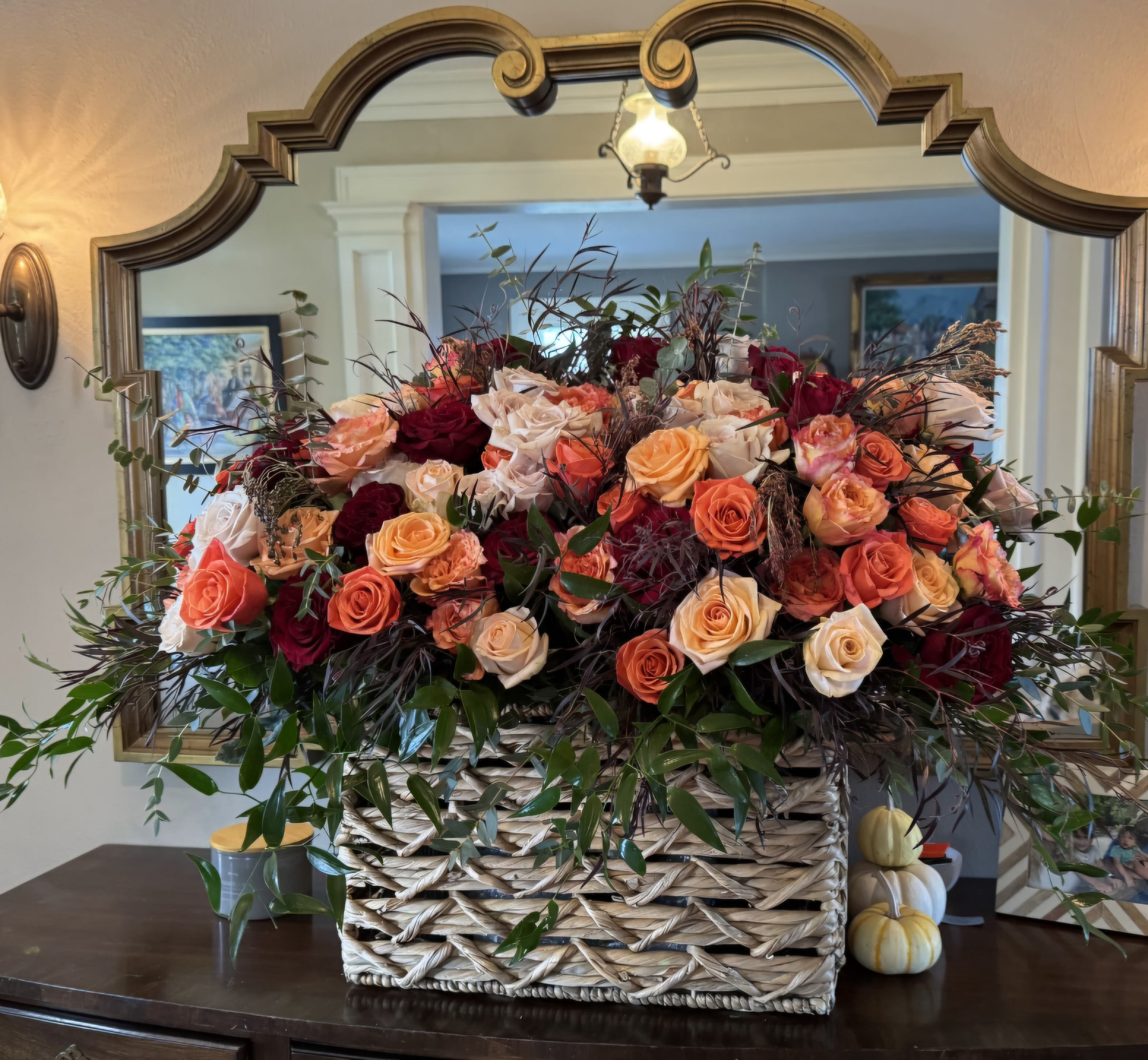 Large basket arrangement of peach, coral, and burgundy roses