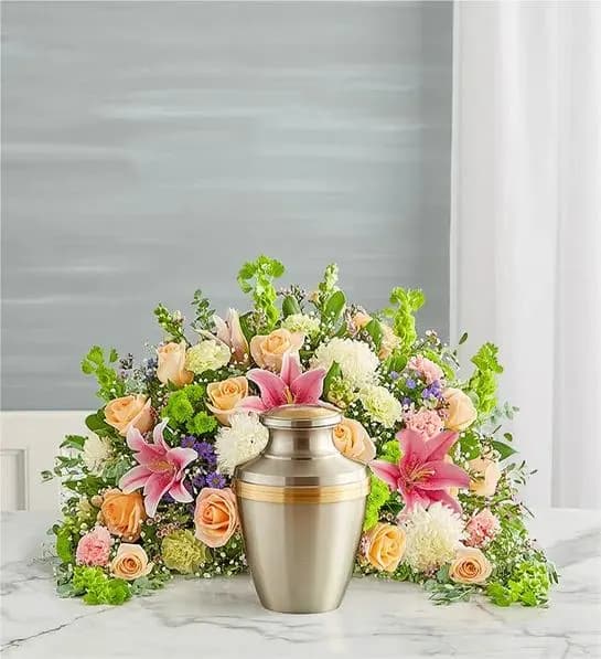 Crescent Cremation Arrangement- Pastel - Express your heartfelt condolences with a beautiful floral tribute. Our crescent shaped design is handcrafted from a soothing cascade of pastel blooms to honor a loved one in a meaningful way.One-sided arrangement of peach roses, pink Oriental lilies, snapdragon and carnations, Bells of Ireland lime green carnations, green button poms, white football mums, purple waxflower and monte 