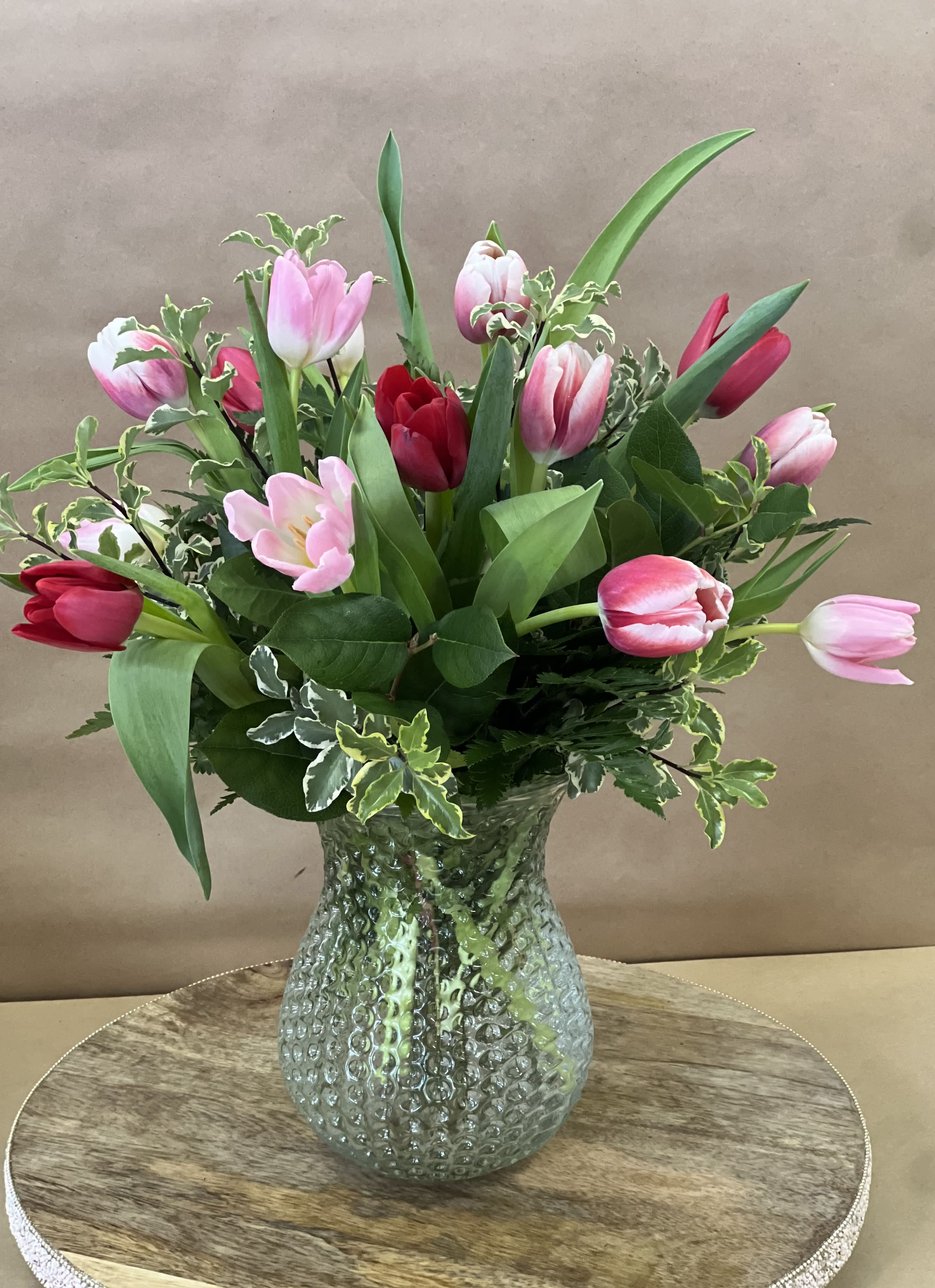 Pink and red tulips arranged in a textured glass vase