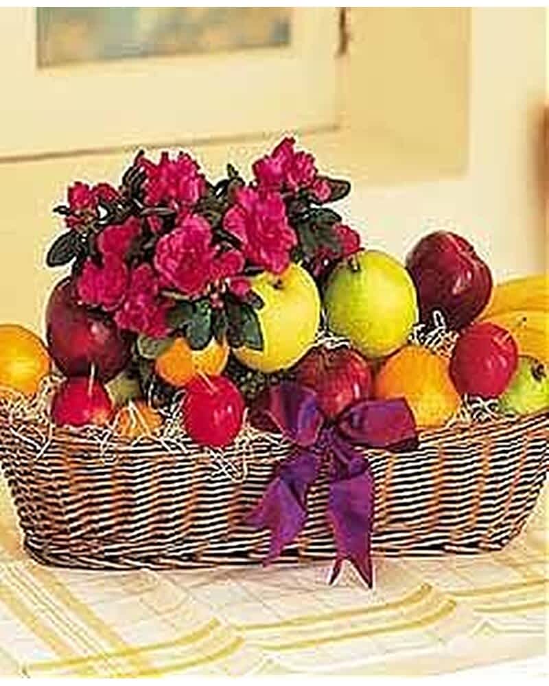 Wicker basket filled with assorted fruit and a pink flowering plant, tied with a purple bow