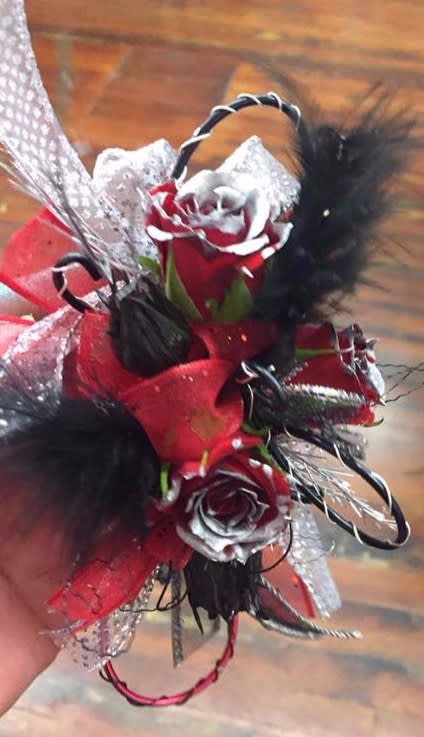 Small red and white rose corsage with black feathers and ribbon