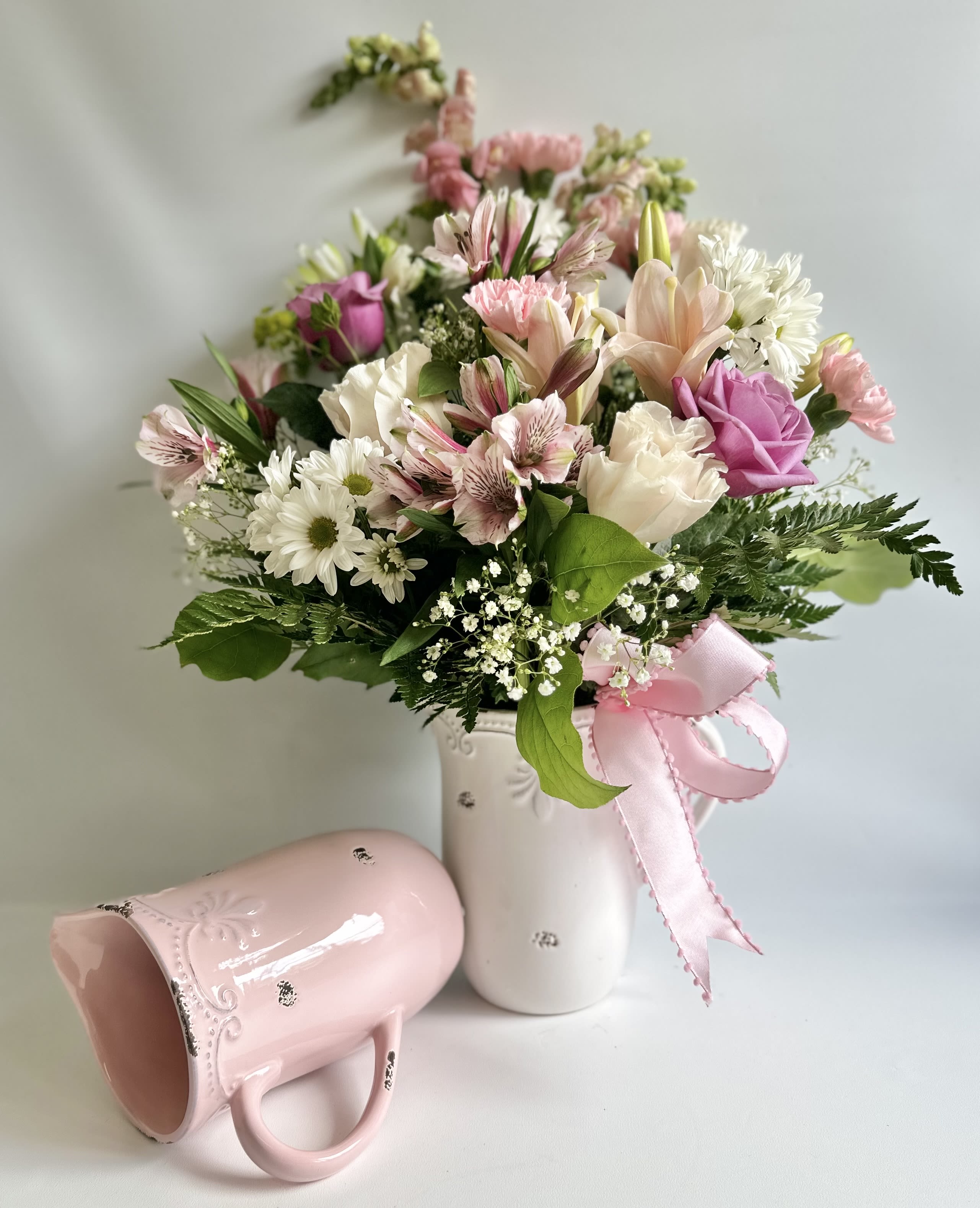 Pink and white mixed bouquet in a white vase with a pink ribbon