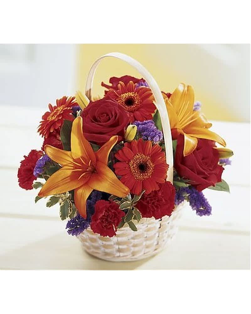 White handled basket of red roses, orange lilies, red gerberas, and purple filler flowers