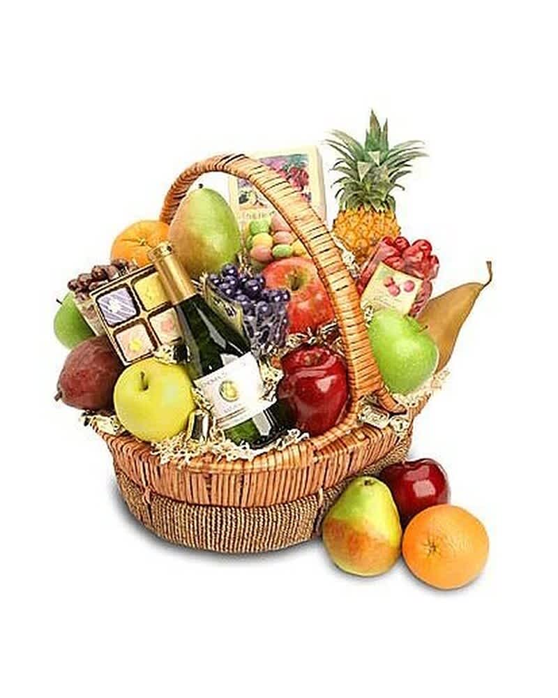 Wicker gift basket filled with assorted fruits, a wine bottle, and gourmet treats