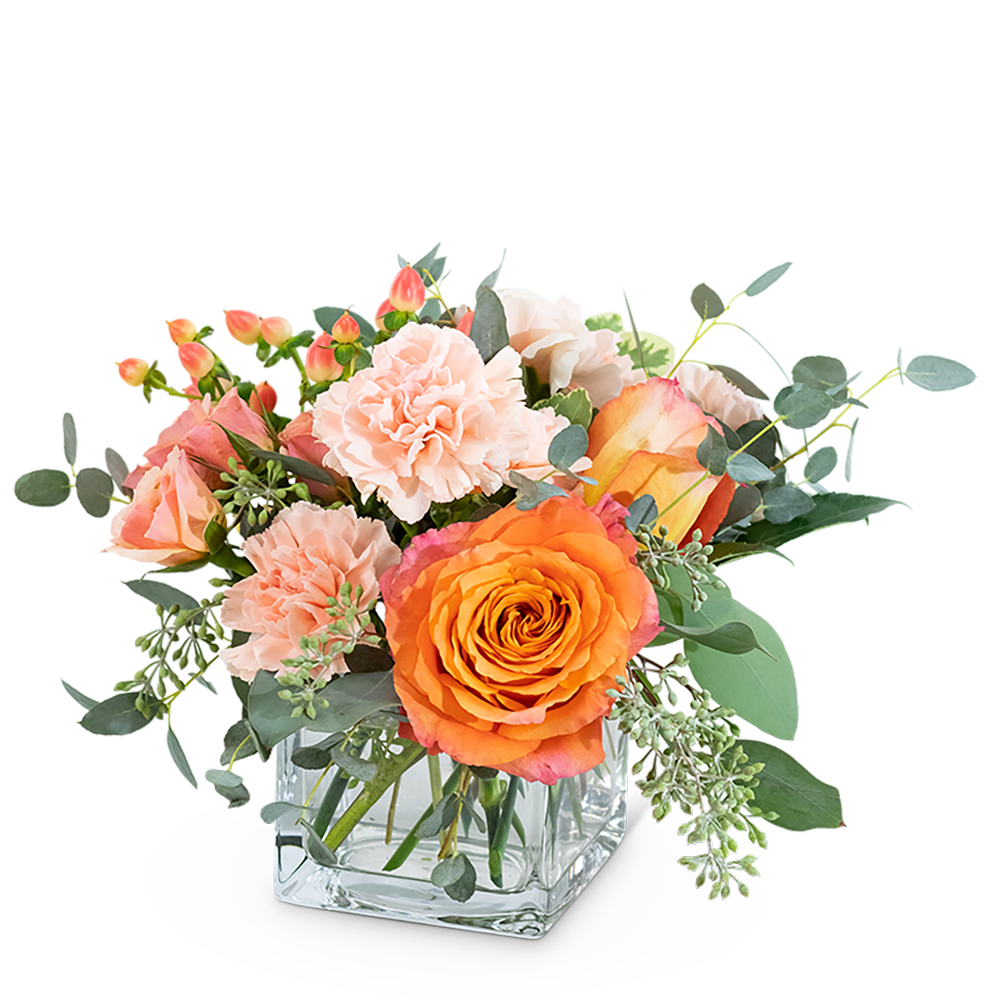 Peach and orange bouquet in a clear square vase