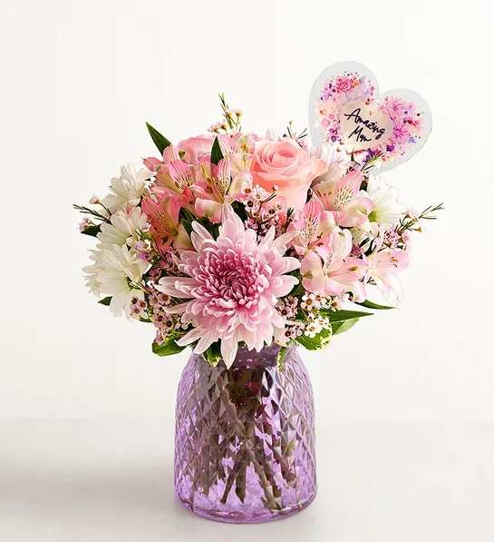 Amazing Mom 225287 - You know she’s amazing; now show her that you know. Roses, Peruvian lilies, daisy poms, and other lush blooms arrive artfully arranged in a lavender glass vase, resulting in a gift as beautifully splendid as she is. You also have the option to add a heart-shape LED pick with the sentiment “Amazing Mom.”
