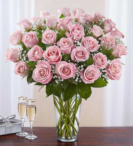 Pink roses arranged in a clear glass vase with baby's breath
