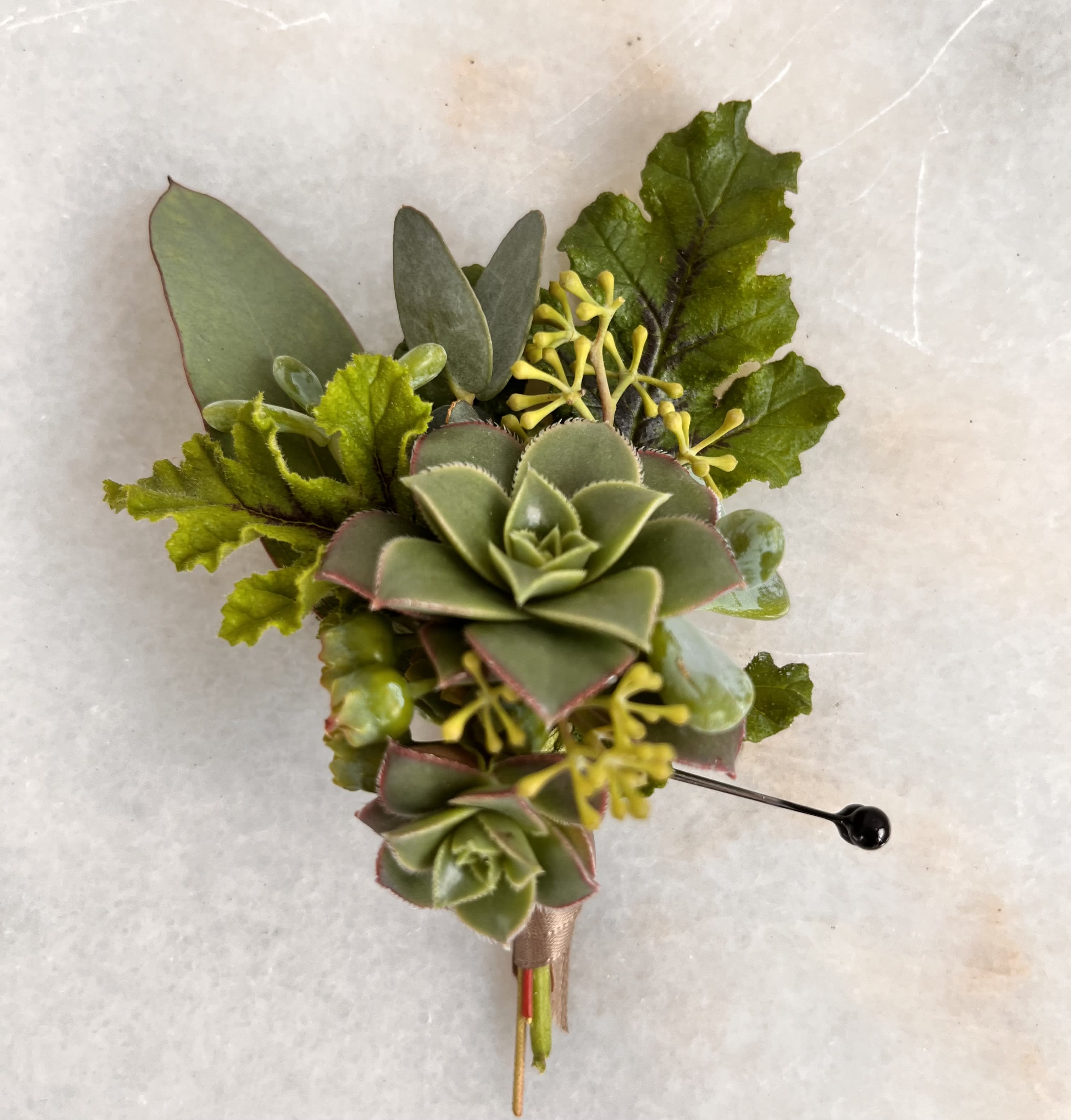 Succulent boutonniere with green foliage and yellow accents