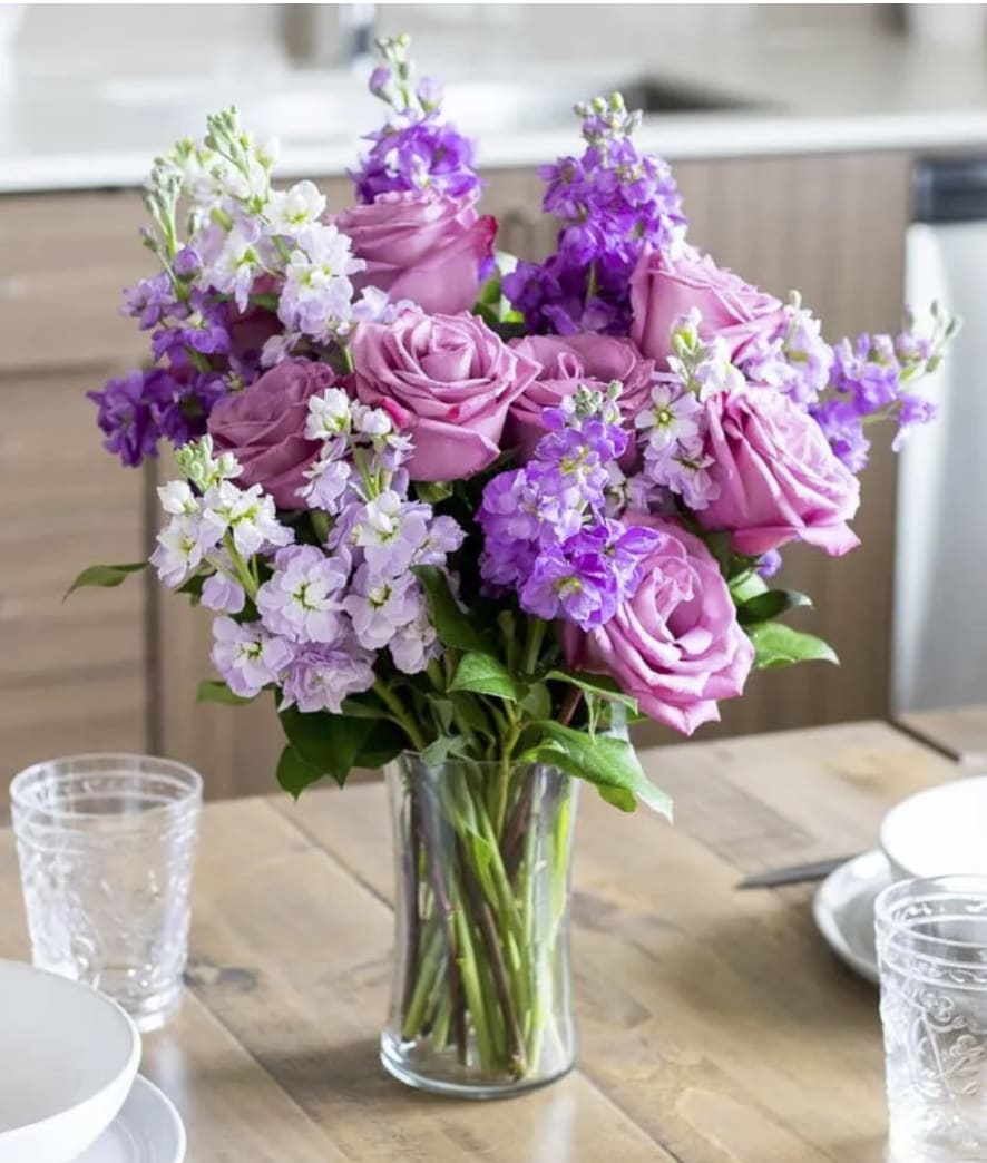 Devoted - Lovely lavender roses, lavender stock, and pink stock are accented with a variety of lush greens in this amazing floral arrangement. Presented in a modern cylinder vase, the bouquet is a wonderful gift to help celebrate an anniversary, a Spring birthday, or just because.   Includes:  • Lavender Roses  • Lavender Stock  • Pink Stock  • Cylinder Vase 
